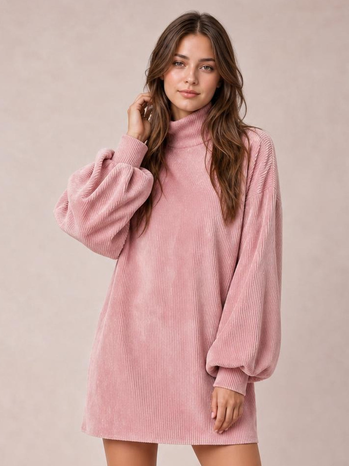 A model poses in a pink ribbed mock neck mini dress with a straight silhouette, long lantern sleeves, and ribbed cuffs.