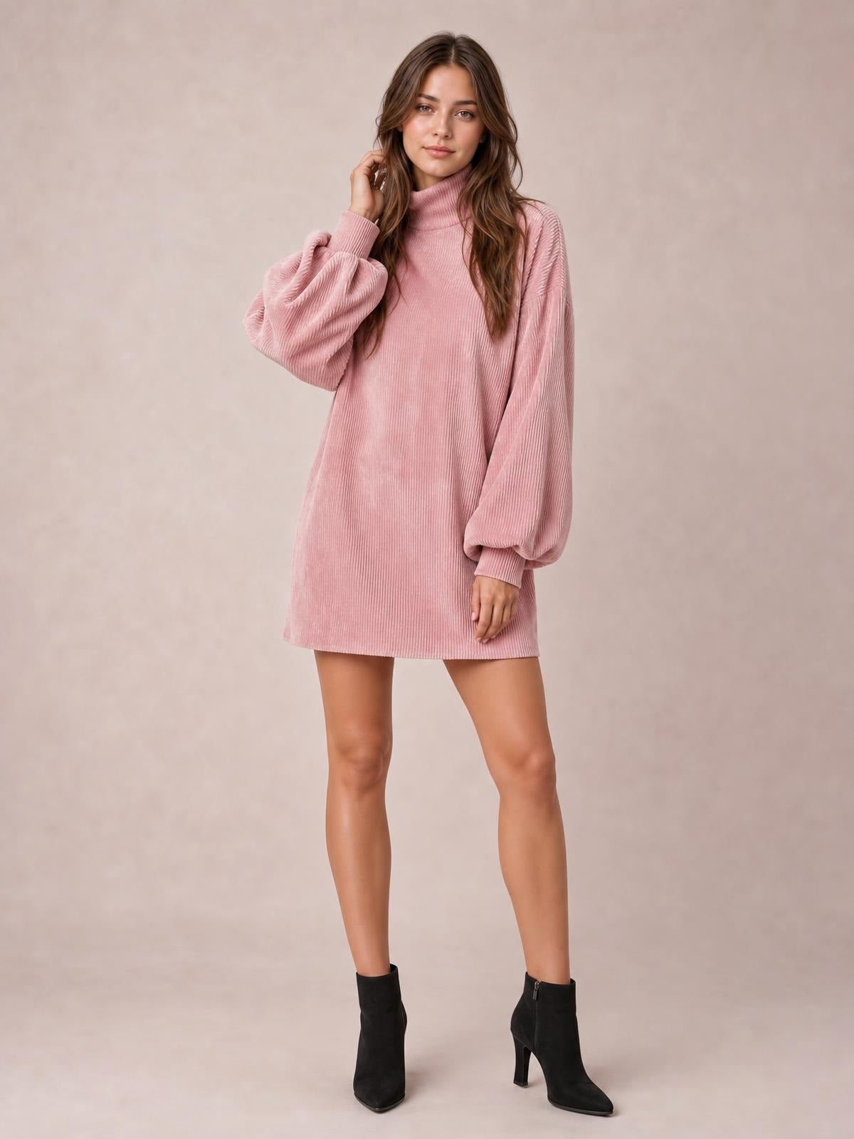 Model poses in a pink ribbed mock neck mini dress with a straight silhouette, voluminous lantern sleeves, and ribbed cuffs.
