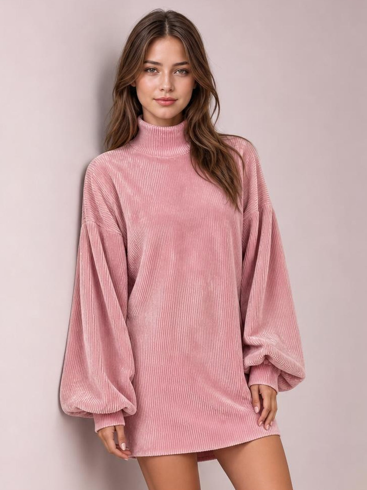 Model poses in a pink ribbed mock neck mini dress with voluminous lantern sleeves, gathered cuffs, and a relaxed straight silhouette.