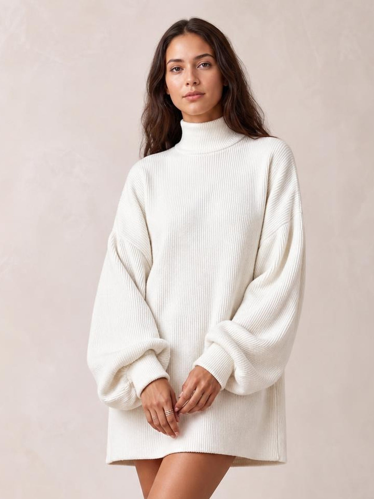 A model stands with hands clasped, wearing a white ribbed mock neck mini dress with voluminous lantern sleeves and a relaxed straight silhouette.