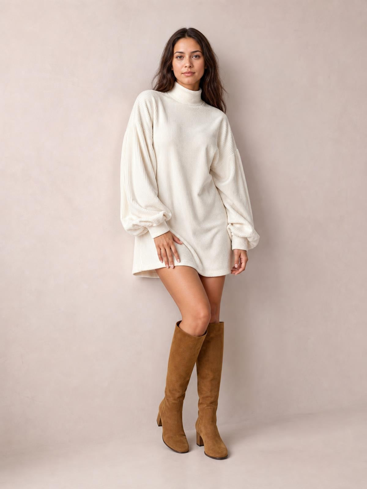 A model poses in a cream ribbed mock neck mini dress with voluminous lantern sleeves, gathered cuffs, and a relaxed straight silhouette.