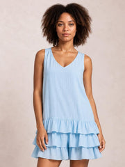 A model wears a light blue sleeveless dress with a V-neck, relaxed silhouette, and multiple tiered ruffled hems.