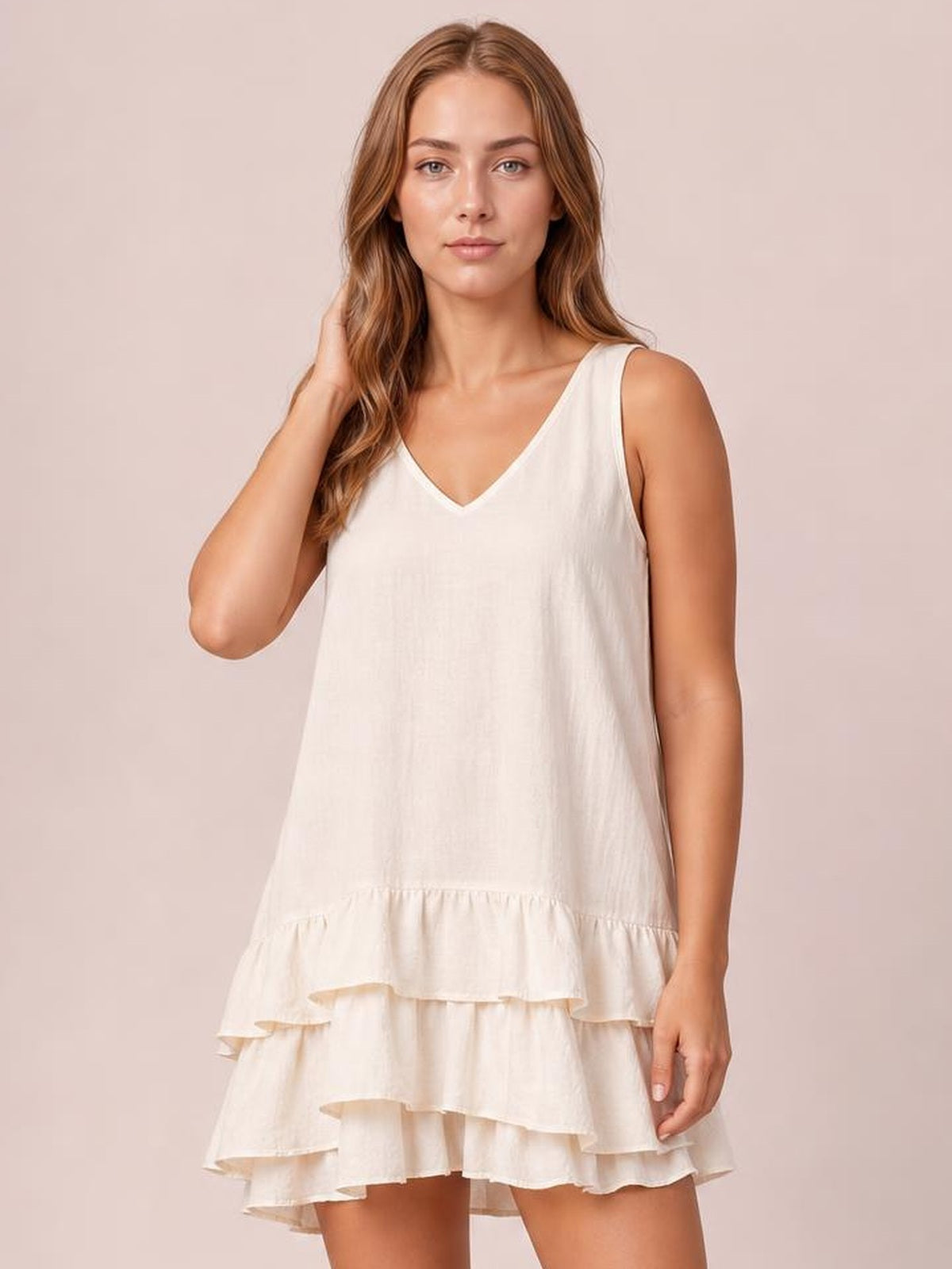 A model poses in an ivory plus-size sleeveless dress with a V-neck, relaxed silhouette, and multiple tiered ruffled hem layers.