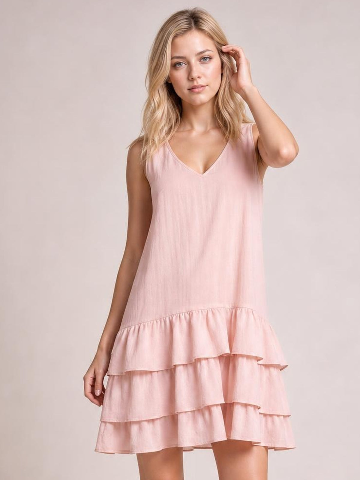 Model poses in a pink sleeveless V-neck dress with a relaxed silhouette and multiple tiered ruffled hems.