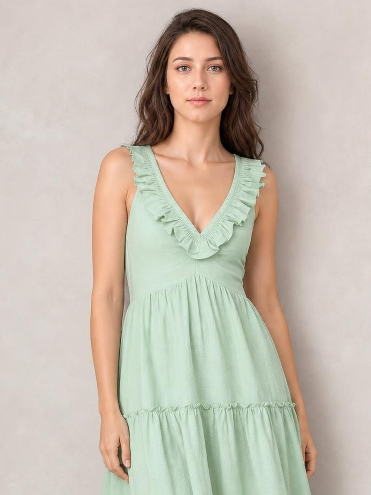 Model wears a mint green ruffled V-neck tiered midi dress with a fitted bodice, gathered waist, sleeveless cut, and flowing A-line silhouette.
