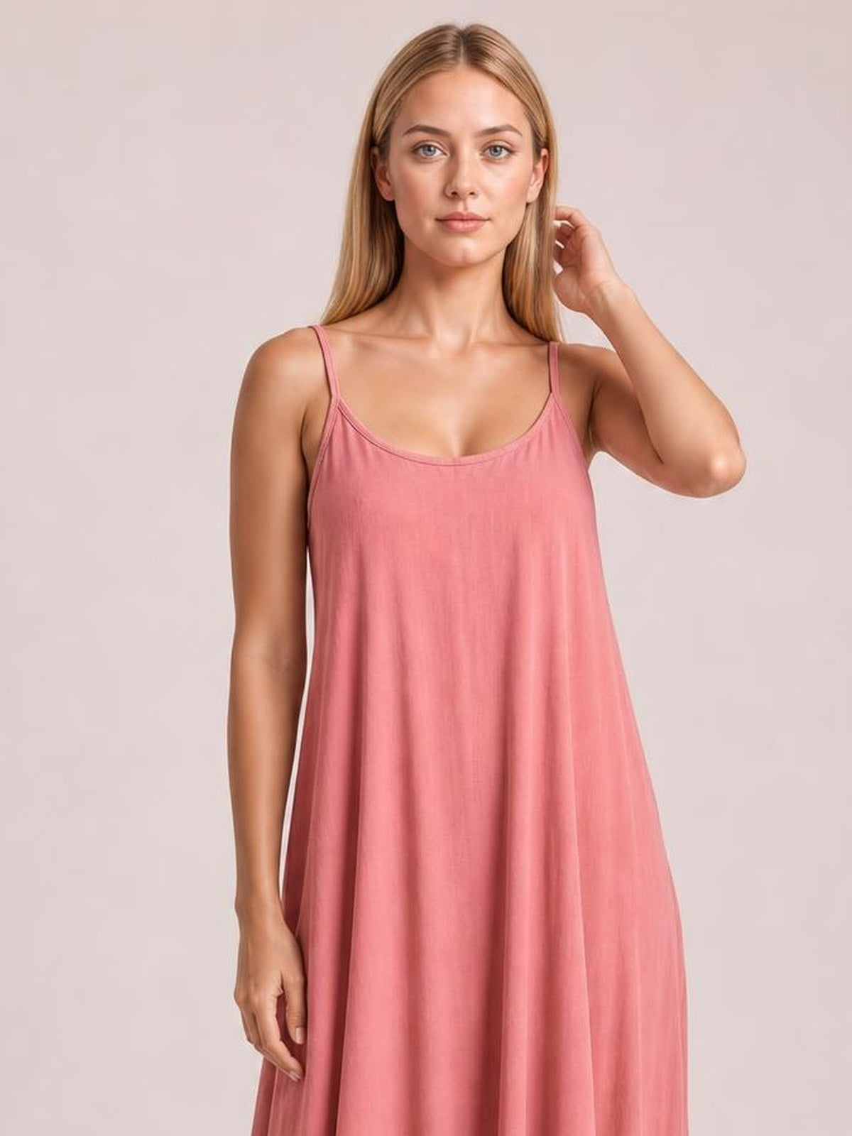Model poses in a pink scoop-neck maxi dress with thin spaghetti straps and a relaxed, flowing silhouette.