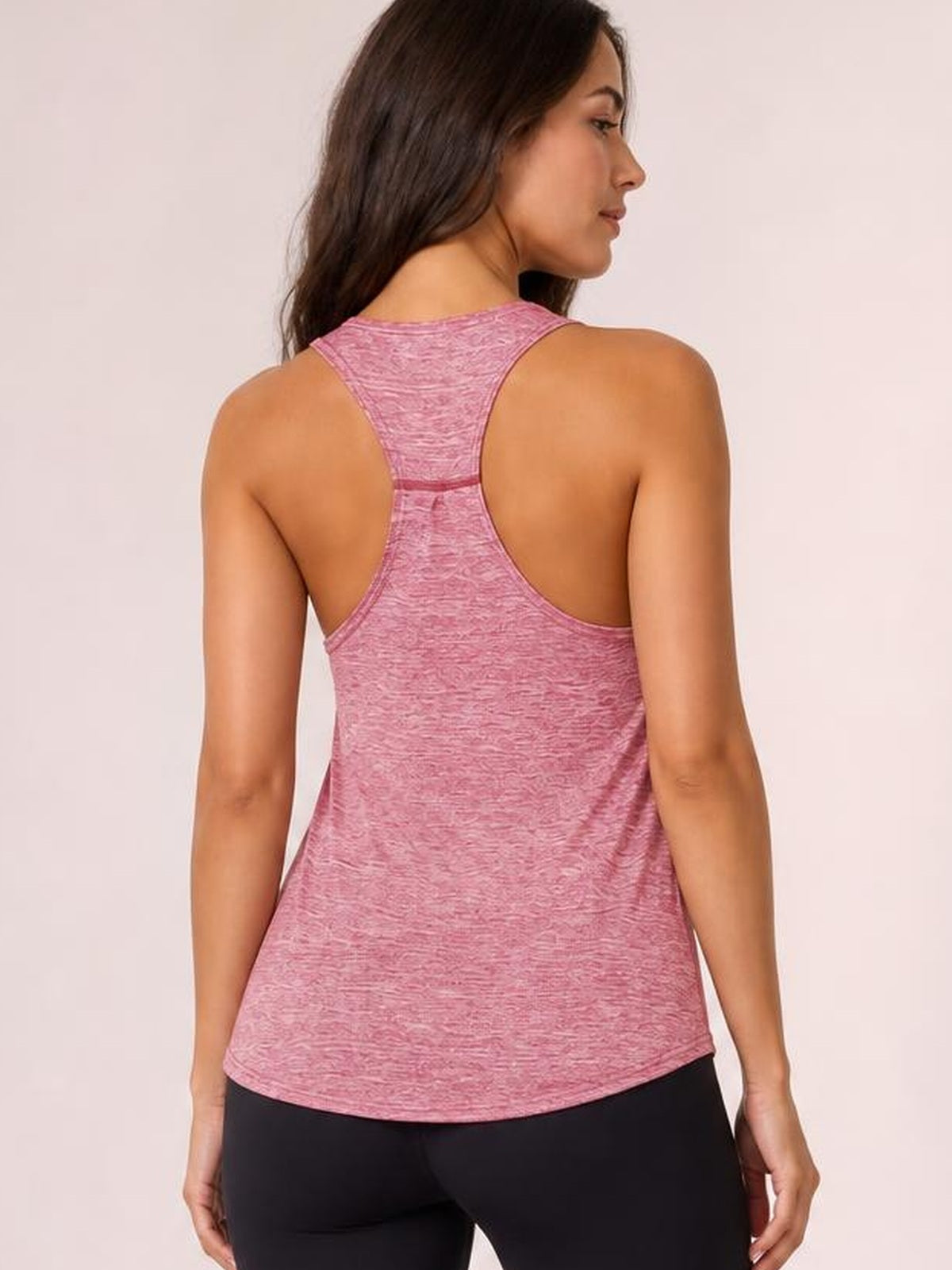 Model shown from the back in a pink active tank with wide racerback straps, a scoop neckline, relaxed silhouette, and curved hem.