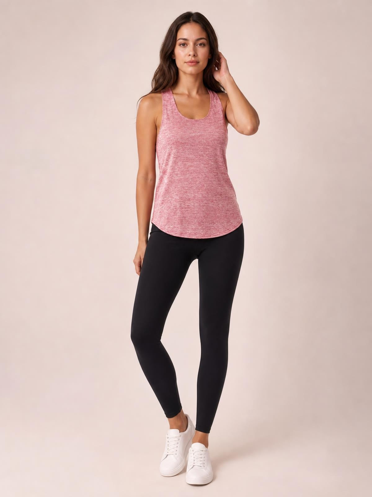 Model wears a pink scoop neck wide strap active tank with a relaxed curved hem and moderate stretch, posing with one hand touching her hair.