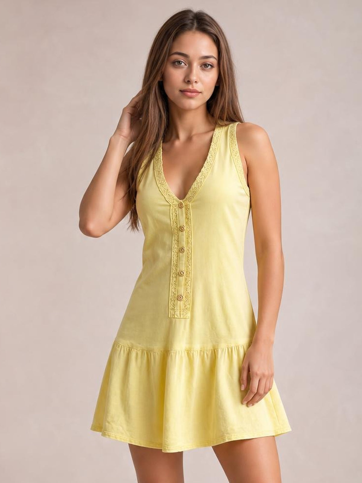 A model poses in a pale yellow sleeveless V-neck mini dress with decorative buttons, textured trim, a fitted bodice, and a gathered flared skirt.