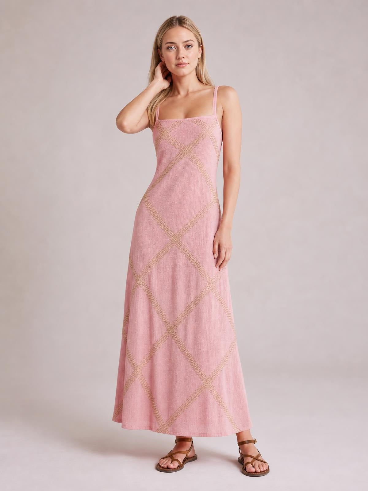A model poses in a pink square-neck maxi dress with slim shoulder straps, a relaxed A-line silhouette, and textured diamond-pattern detailing.