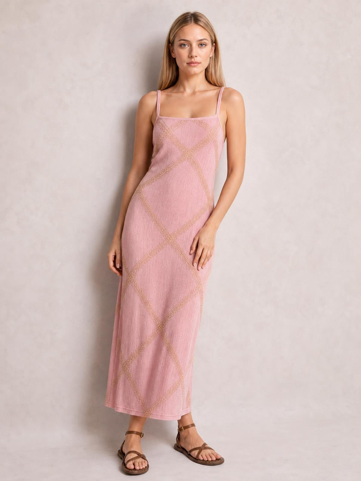 A model stands in a pink square-neck maxi dress with thin straps, a sleeveless straight silhouette, and textured geometric line detailing.