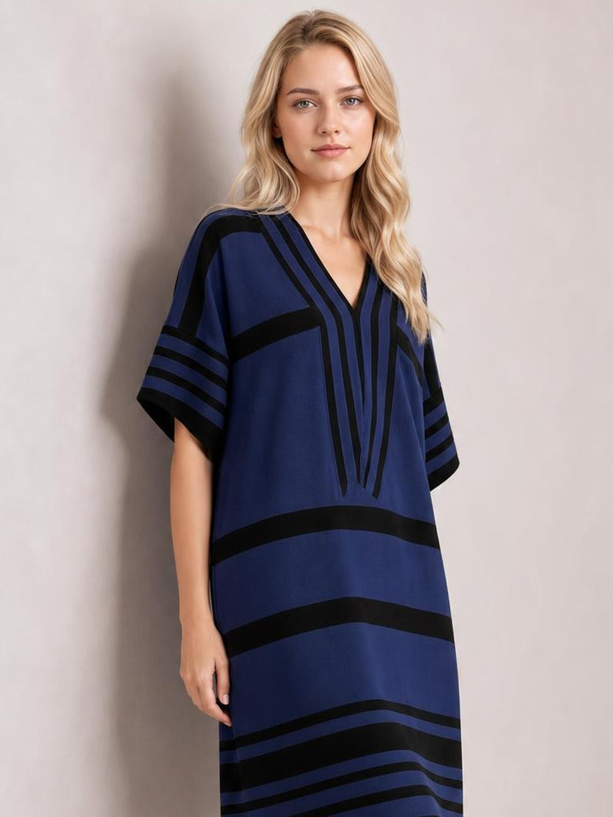 Model wears a navy blue striped half-sleeve midi dress with a loose straight silhouette, V-neckline, and bold black geometric bands.