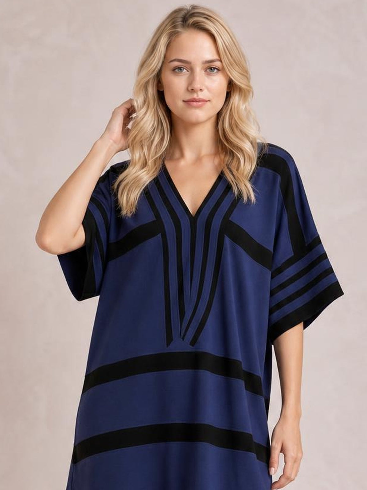 Model poses with one hand in her hair wearing a navy and black striped plus-size midi dress with a V-neck, half sleeves, and a relaxed straight silhouette.