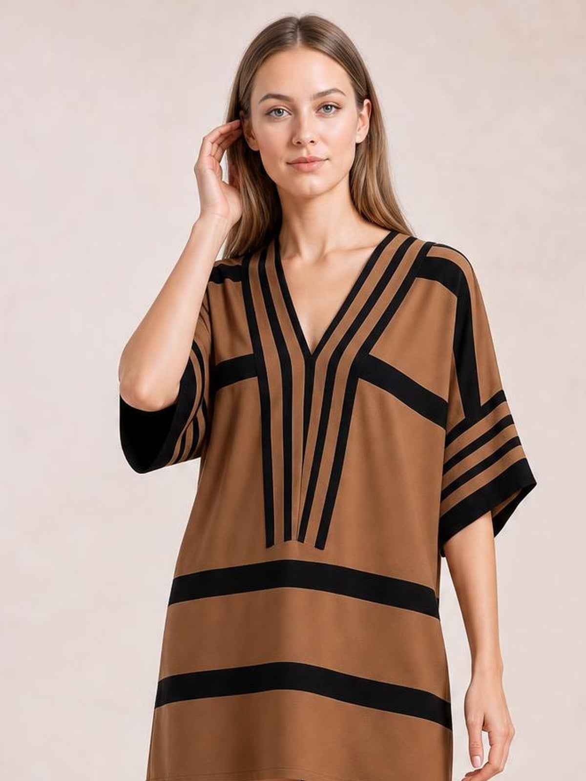 A model poses in a brown and black striped midi dress with a V-neck, half sleeves, relaxed straight silhouette, and bold geometric stripe construction.