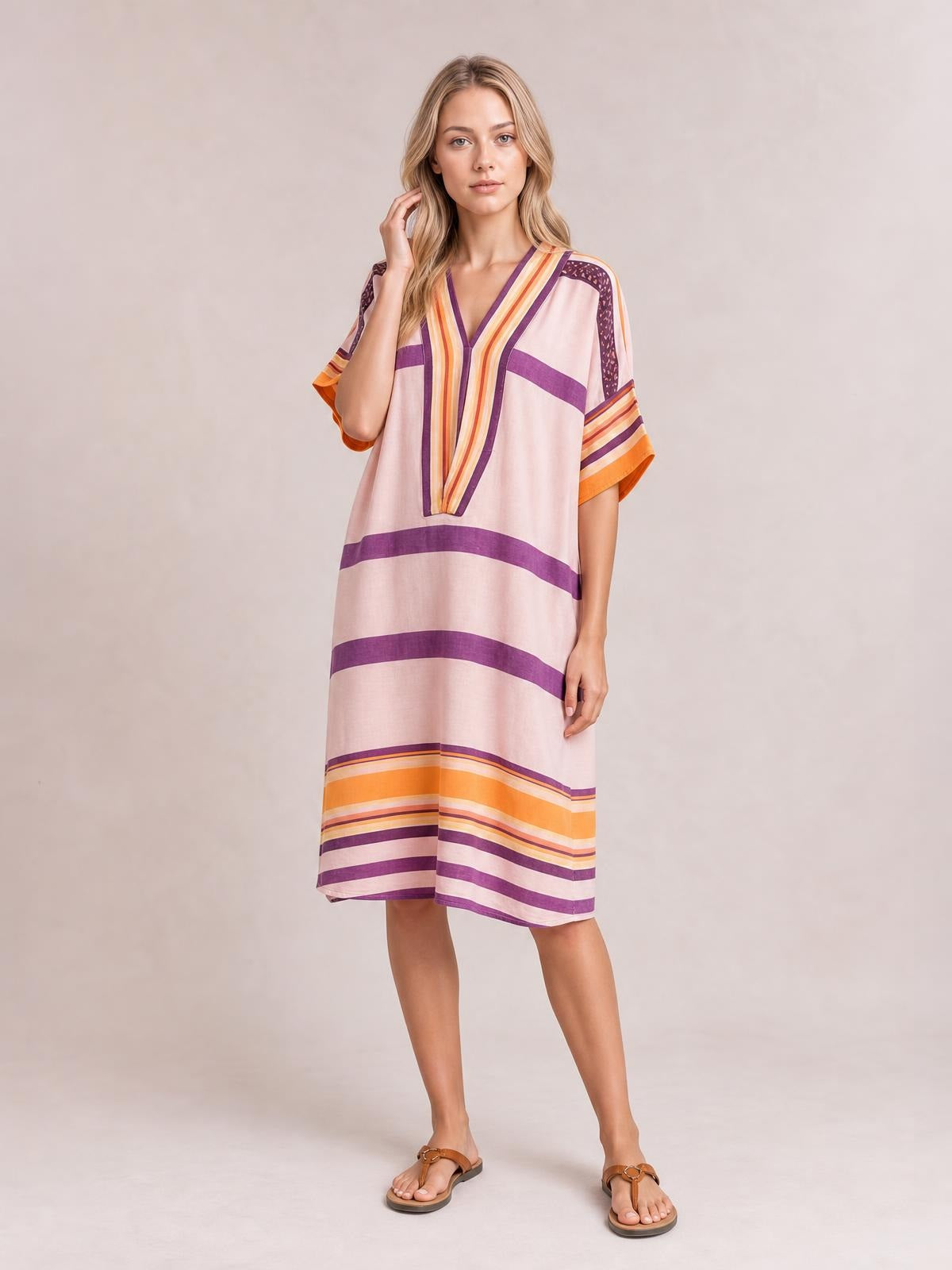 Model poses in a loose pink striped midi dress with purple and orange accents, half sleeves, a V-neckline, and a relaxed straight silhouette.
