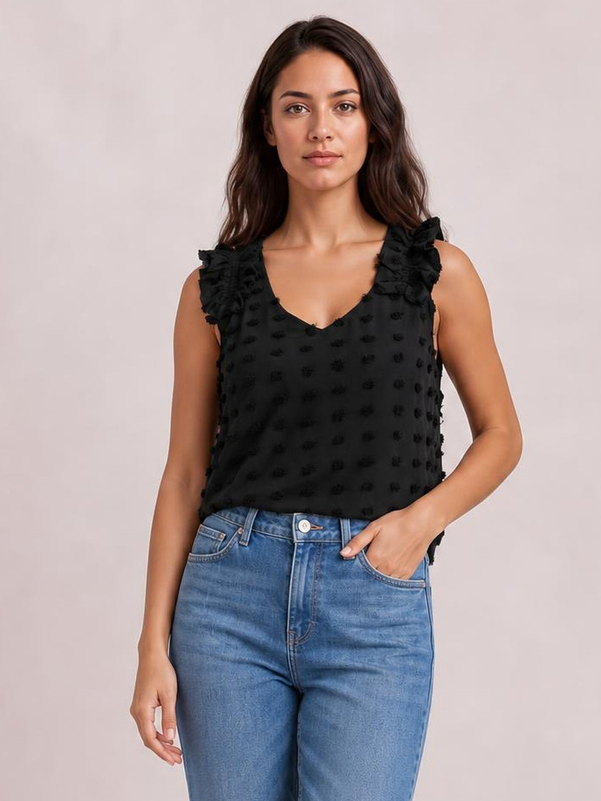 Model wears a black Swiss dot V-neck tank with ruffled shoulder straps, a relaxed straight silhouette, and textured raised dot detailing, paired with jeans.