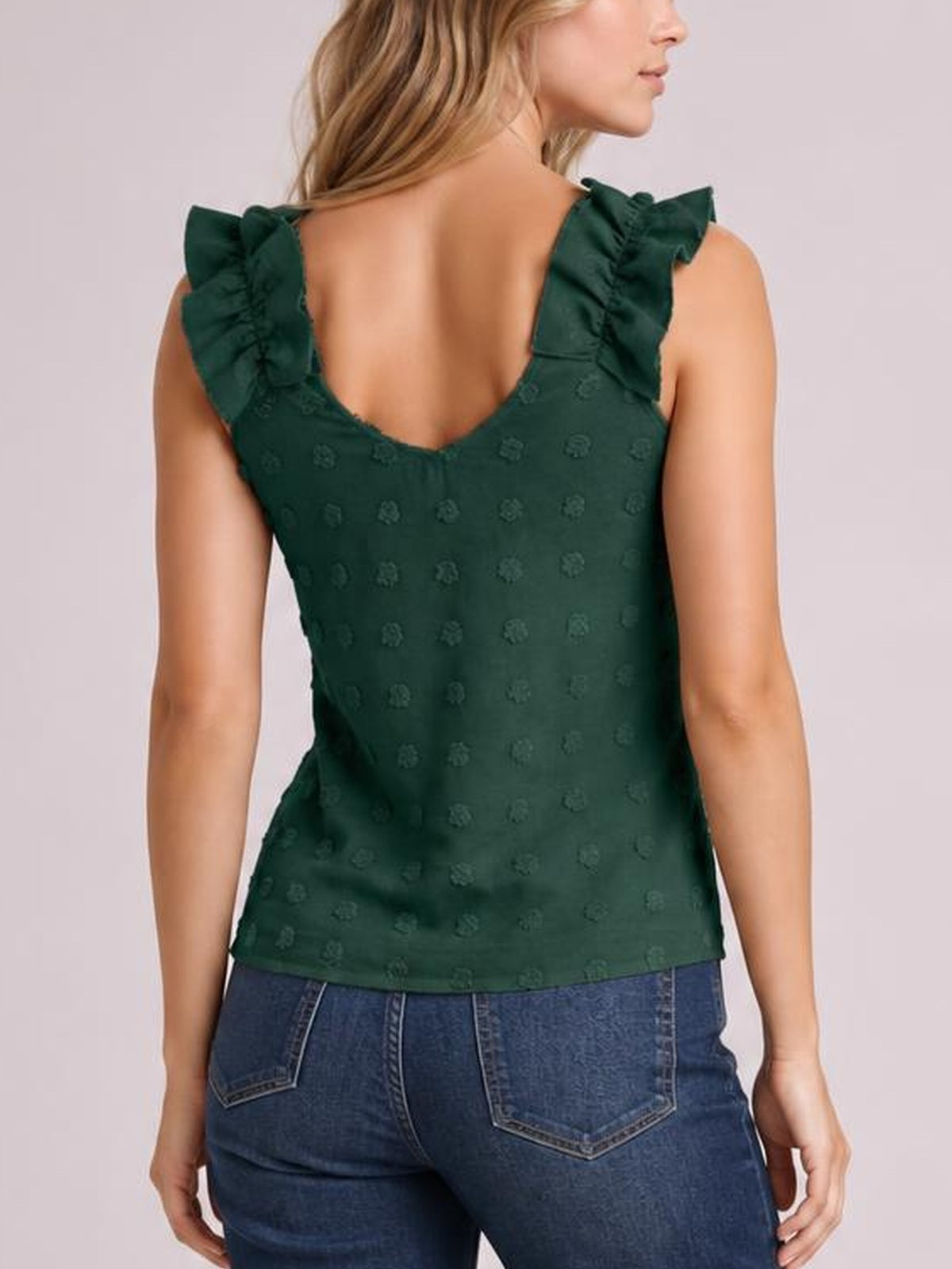 A model shows the back of a dark green Swiss dot tank with a V-shaped neckline, ruffled shoulder straps, and a straight, relaxed silhouette.