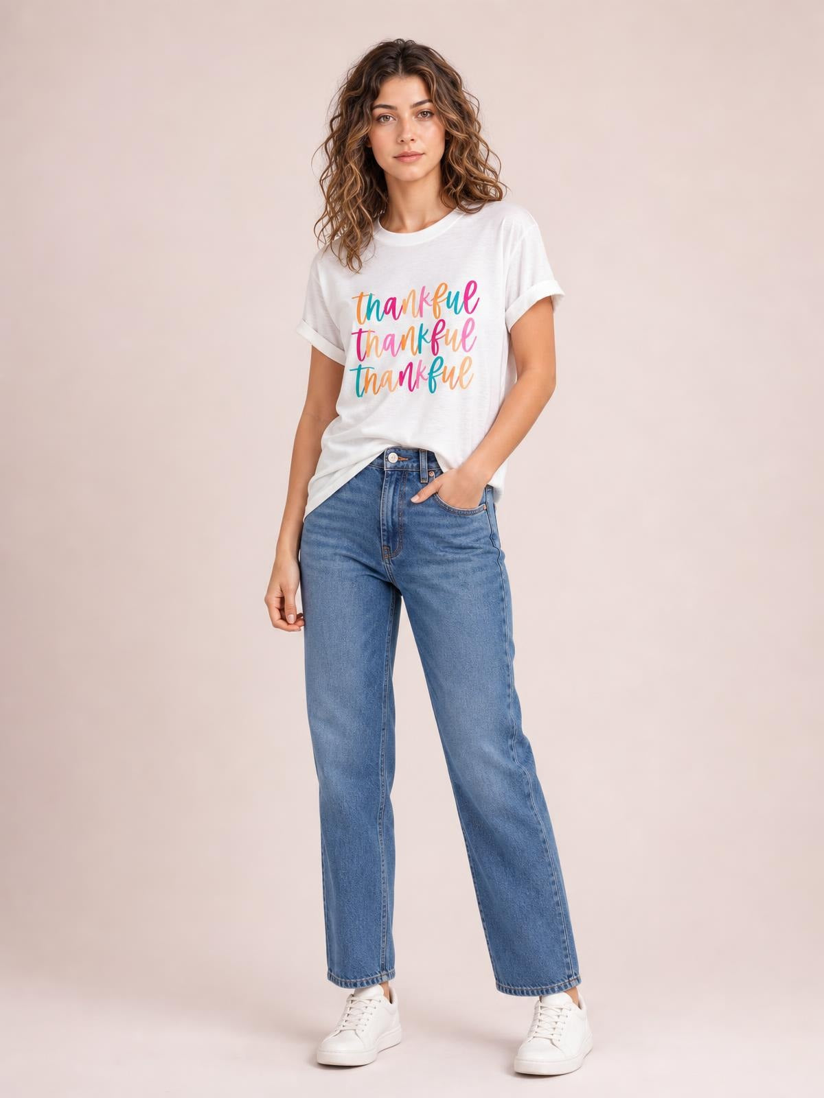 A model poses in a white THANKFUL round-neck short-sleeve T-shirt with colorful graphic lettering, rolled sleeve cuffs, and a relaxed silhouette.