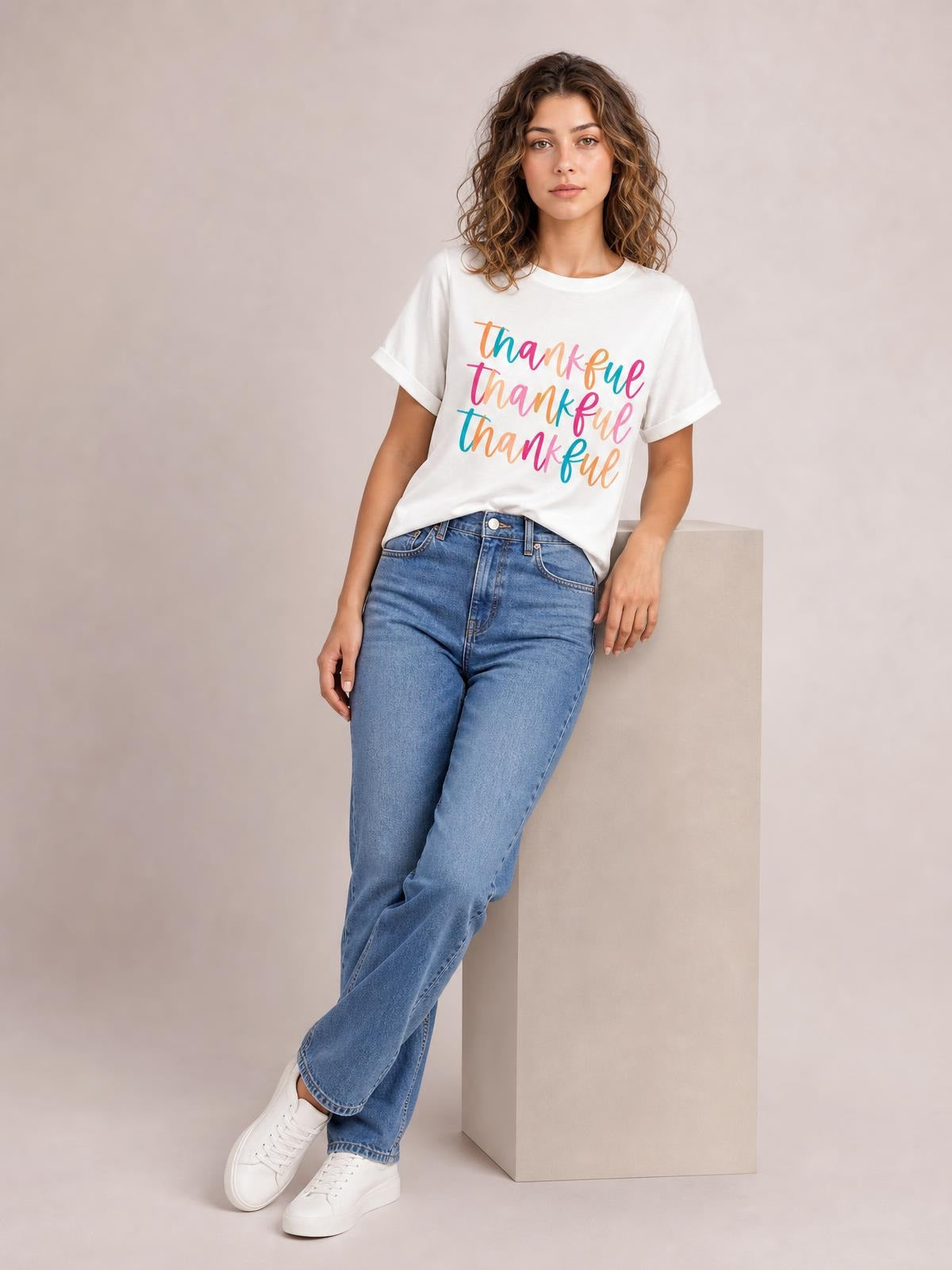 Model wears a white THANKFUL round-neck short-sleeve T-shirt with rolled cuffs and colorful stacked lettering in a relaxed fit.