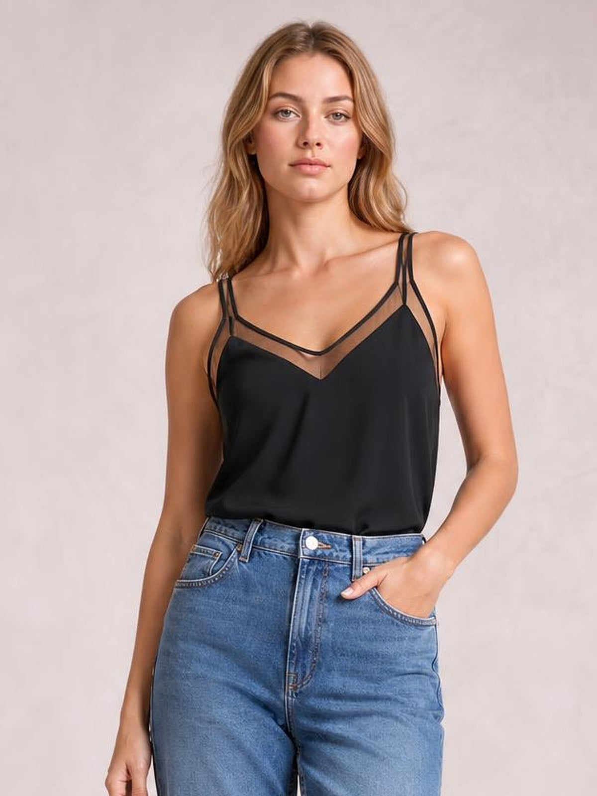 Model wears a black V-neck spaghetti strap cami with a semi-sheer neckline, relaxed silhouette, and layered strap construction, paired with jeans.