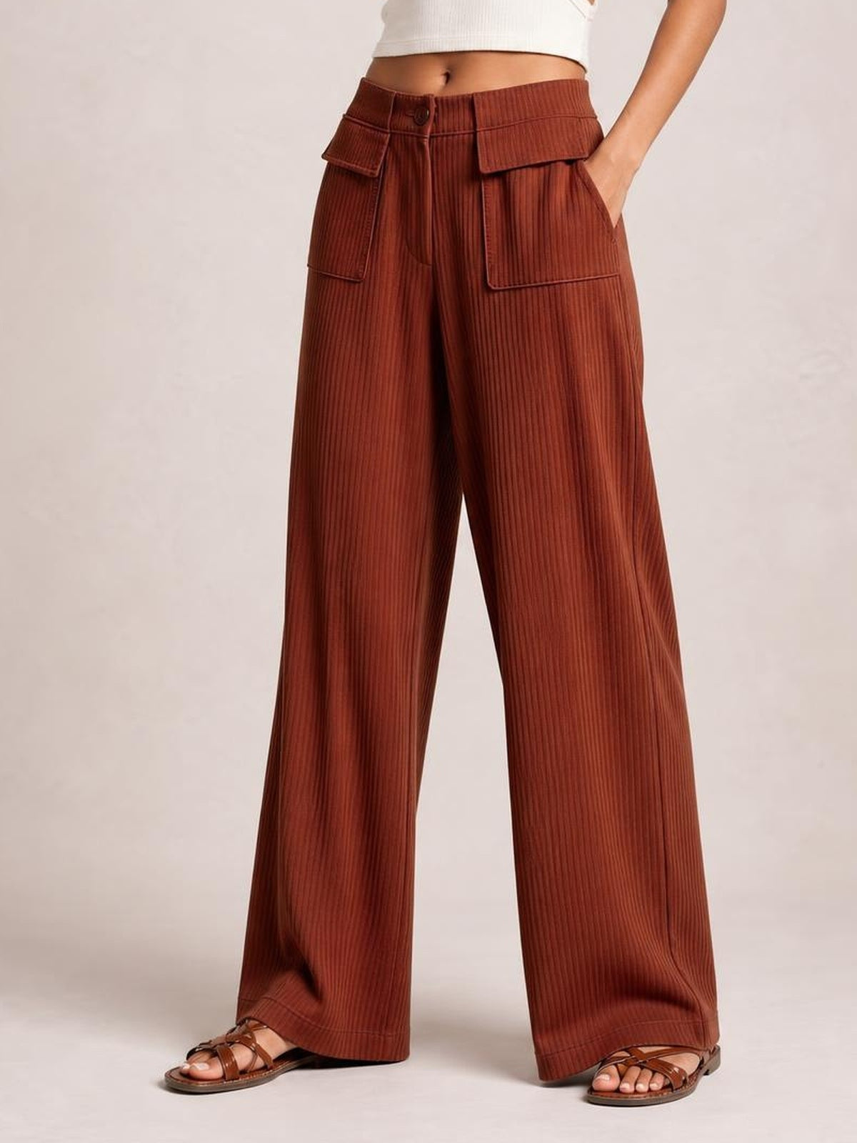 Model wearing rust-brown wide-leg corduroy pants with a button waist, belt loops, oversized patch pockets, and relaxed full-length legs.