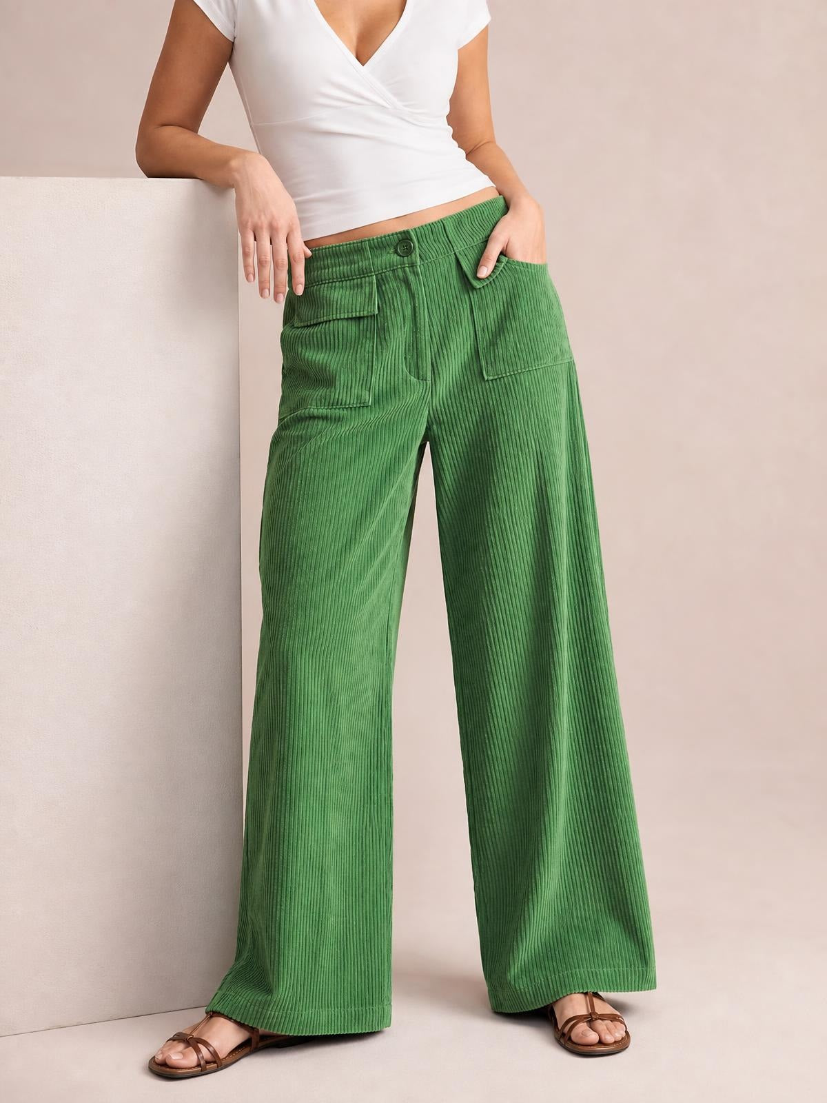 Model wearing green wide-leg corduroy pants with a drawstring waist, button closure, and multiple front pockets, posed with one hand in a pocket.