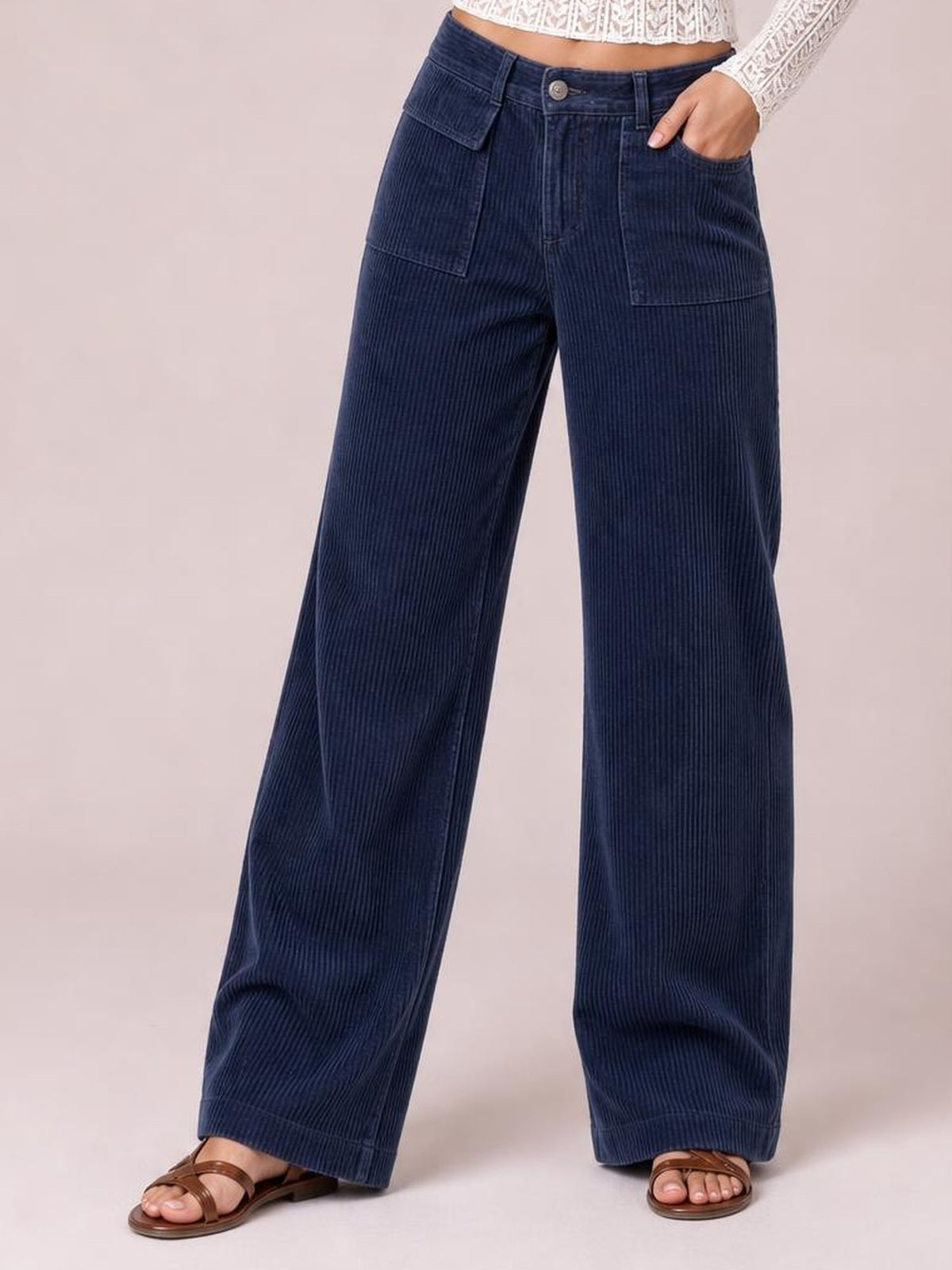 Model stands in navy wide-leg corduroy pants with a high-rise button waist, belt loops, front patch pockets, and relaxed full-length legs.