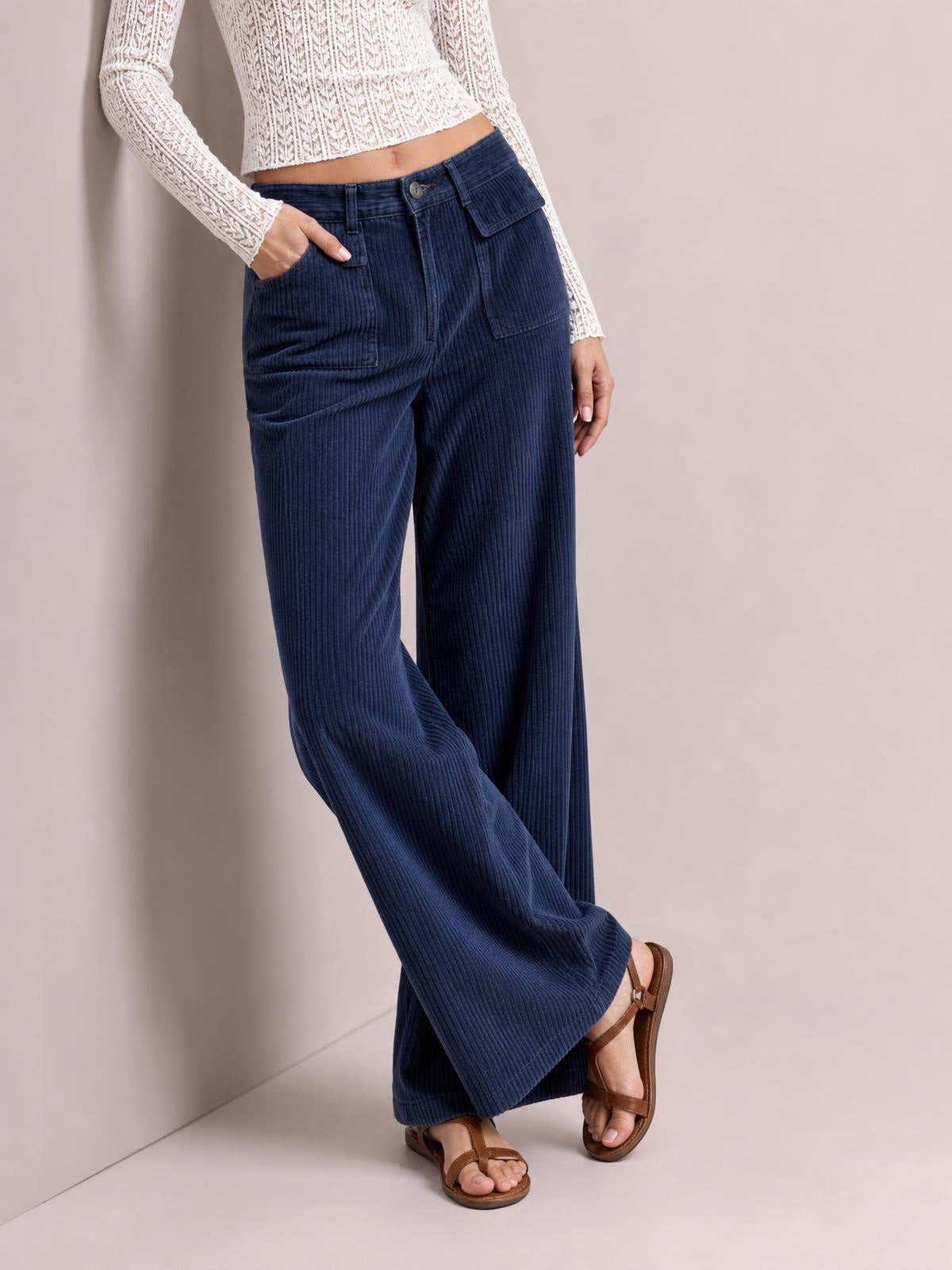 Model poses in navy blue wide-leg corduroy pants with vertical ribbing, belt loops, front pockets, and a button-fly waistband.