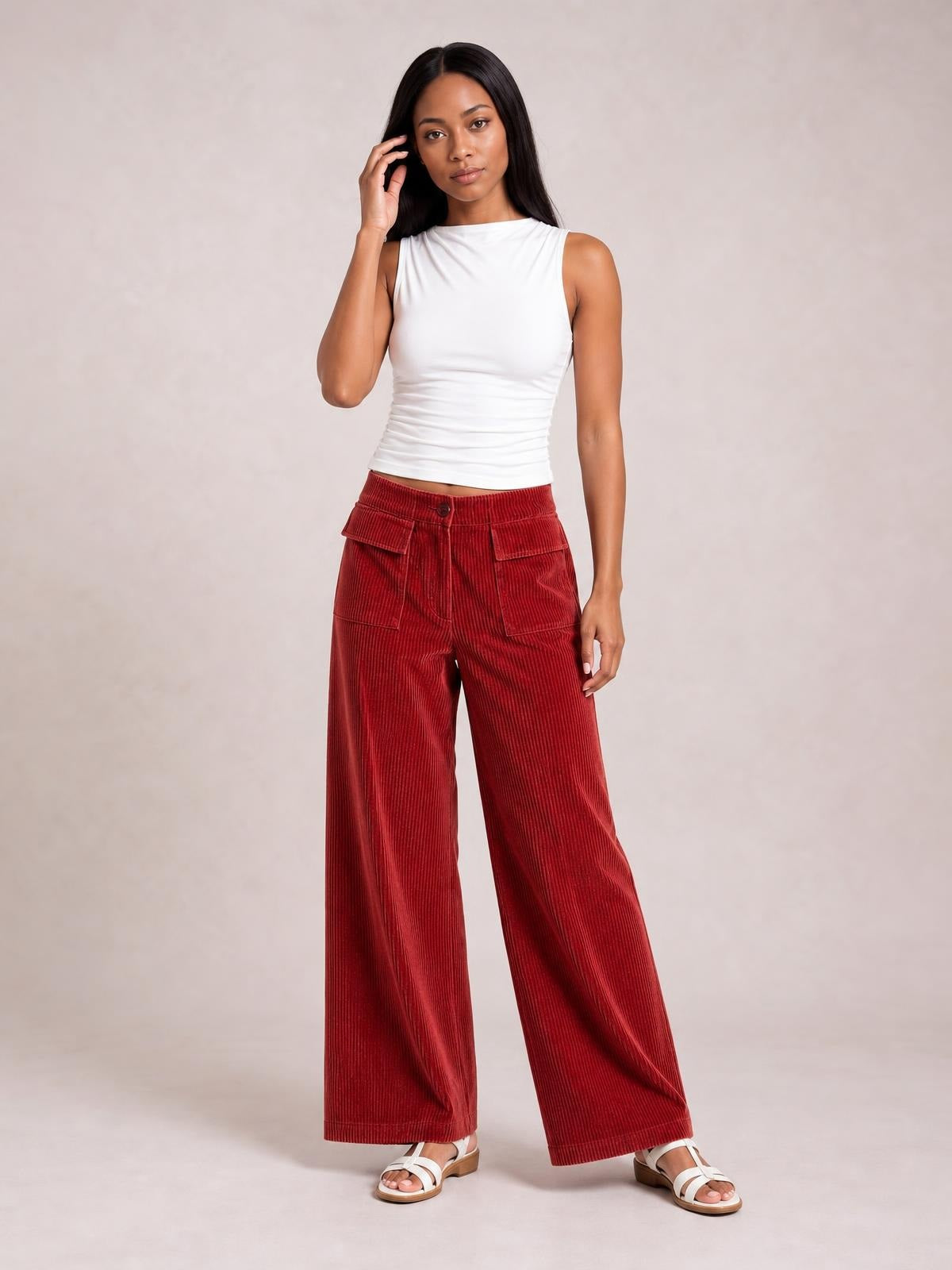 Model poses in red corduroy wide-leg pants with a button waist, front patch pockets, and a relaxed full-length silhouette.
