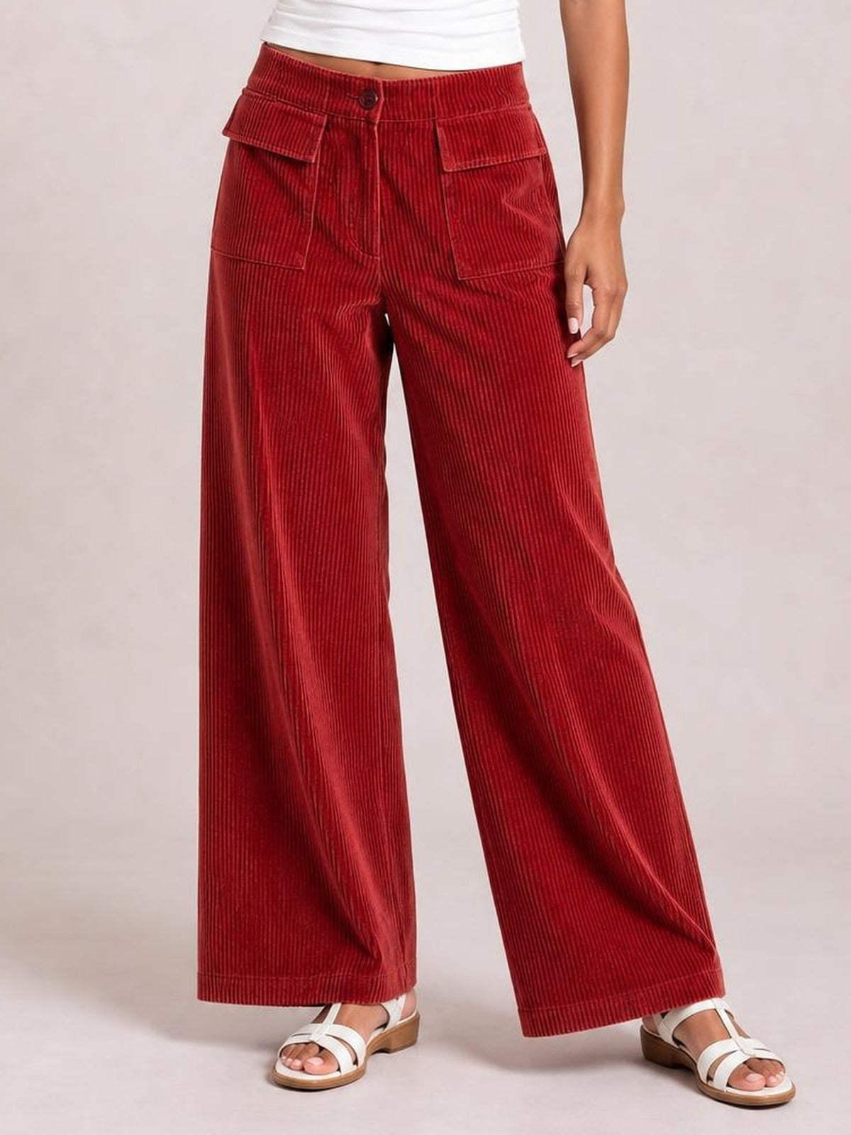 Model wearing red wide-leg corduroy pants with a high-rise button waist, front patch pockets, and a relaxed full-length silhouette.