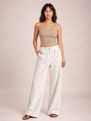 A model stands in cream wide-leg corduroy pants with a high waist, button closure, and large patch pockets, one hand tucked into a pocket.