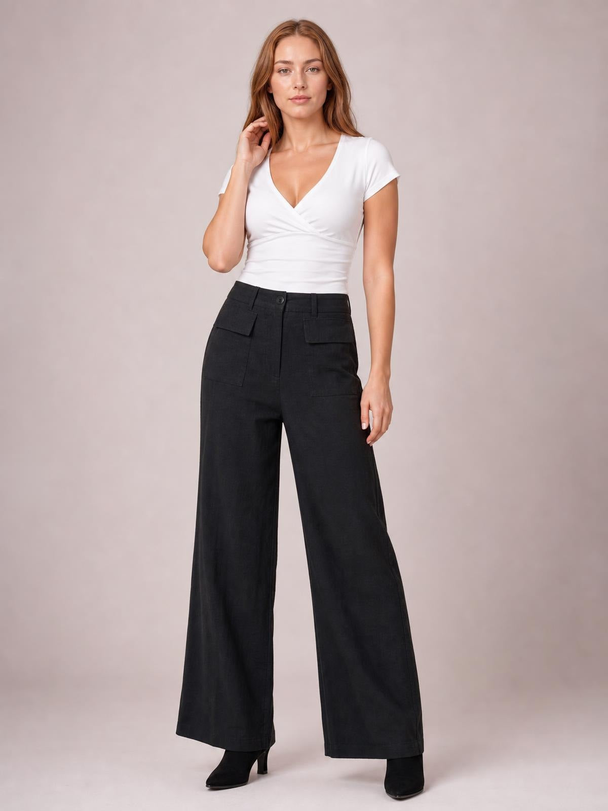 Model poses in black wide leg pants with a high-rise button waistband, belt loops, and large front patch pockets.