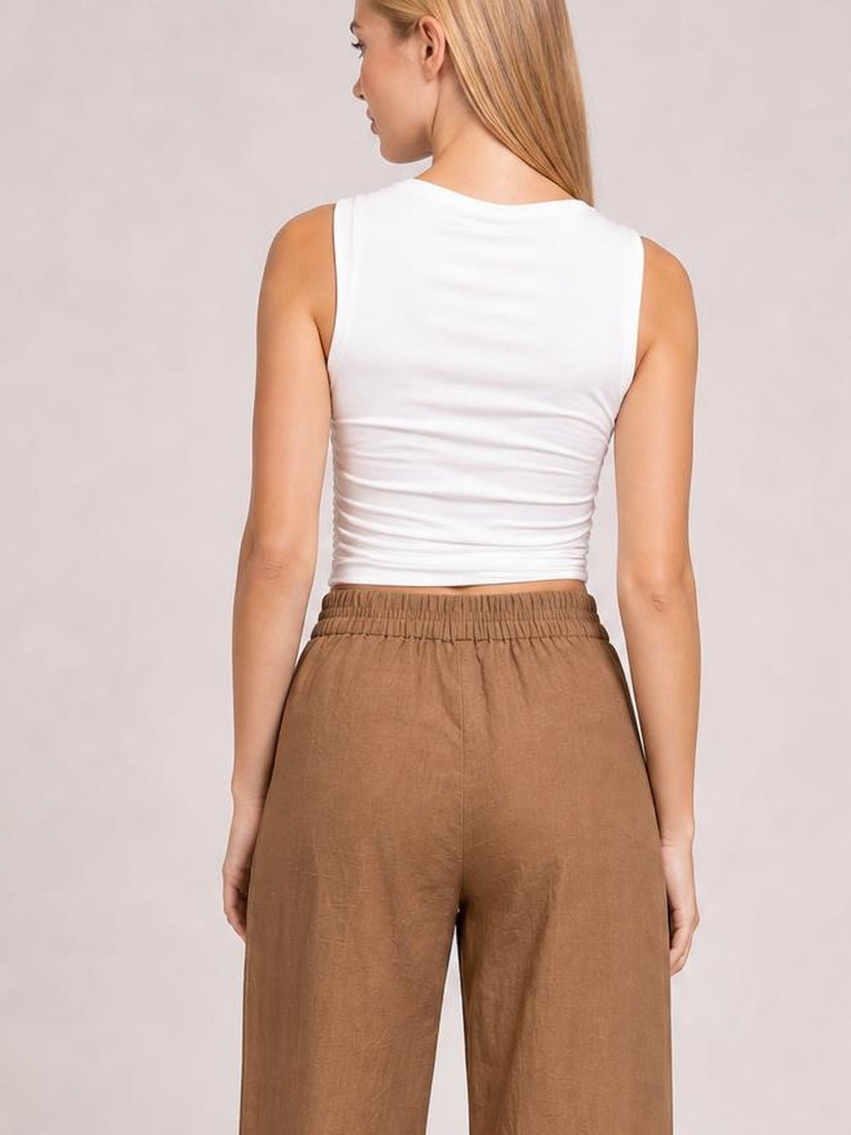 Model shown from the back wearing brown wide-leg pants with an elasticized waistband and relaxed, flowing silhouette.