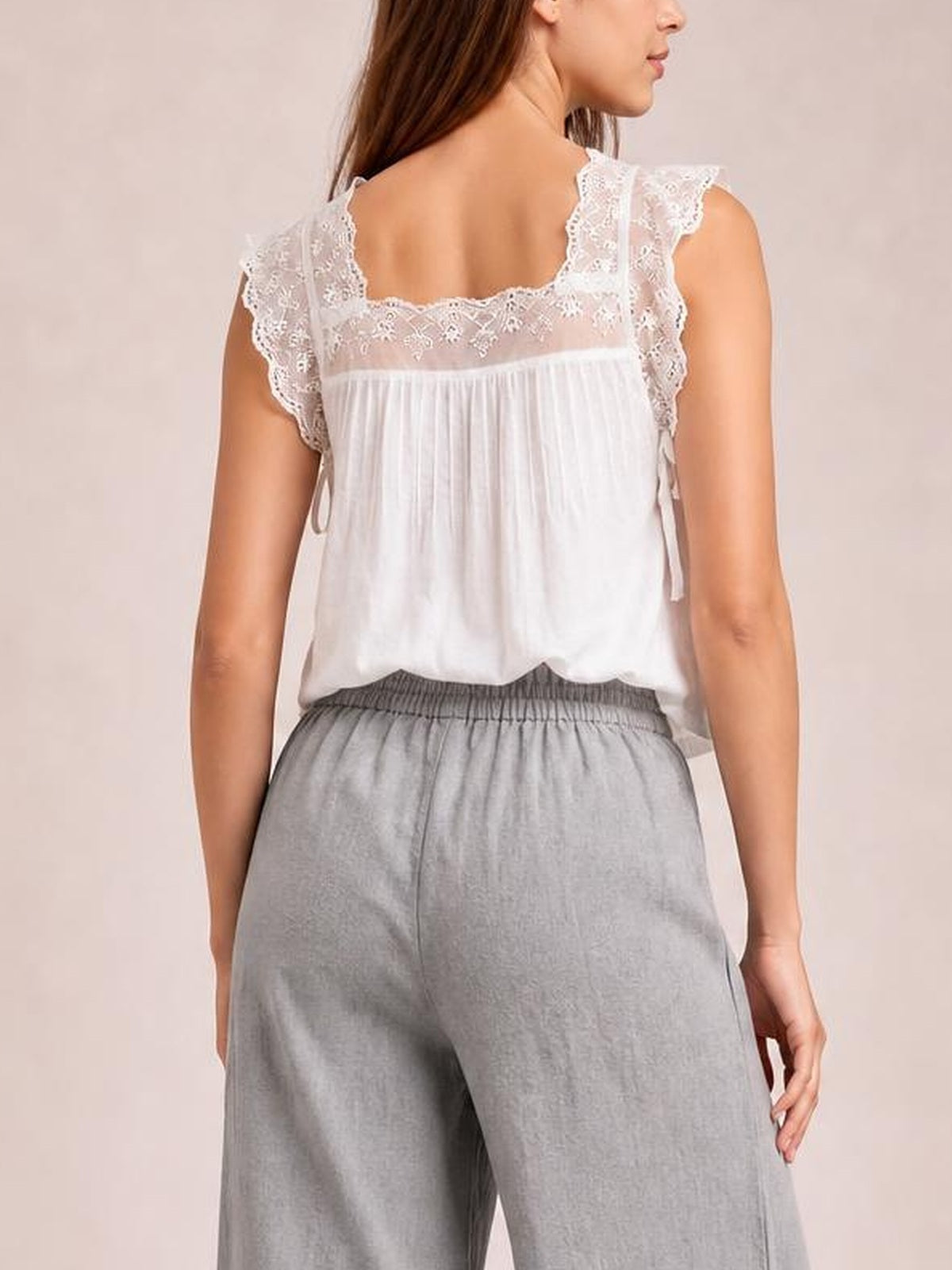 A model shown from behind wears light gray wide leg pants with a relaxed silhouette, soft drape, and gathered elastic waistband.