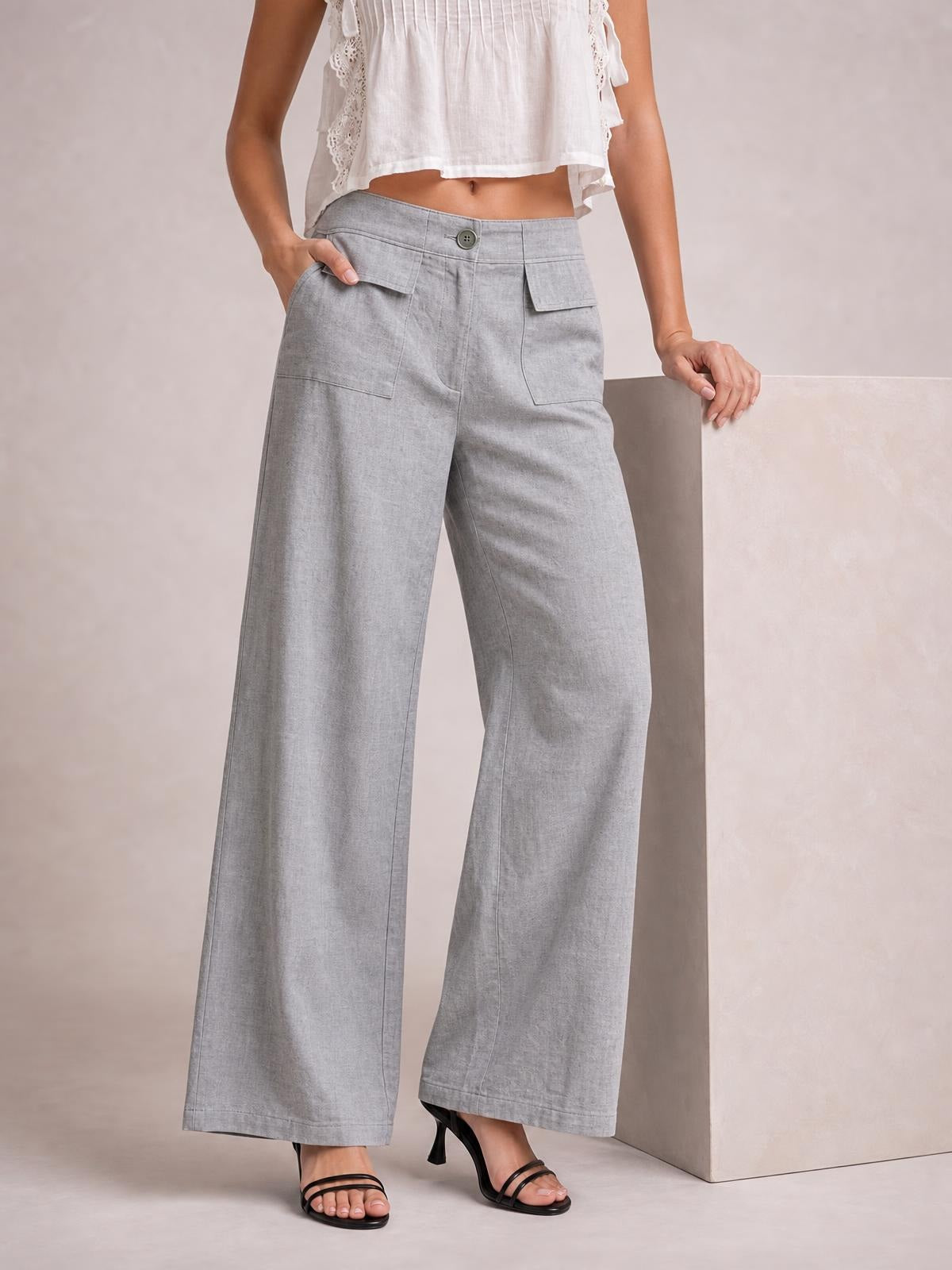 Model wearing light gray wide leg pants with a buttoned waistband, flap cargo pockets, side pockets, and straight flowing legs.