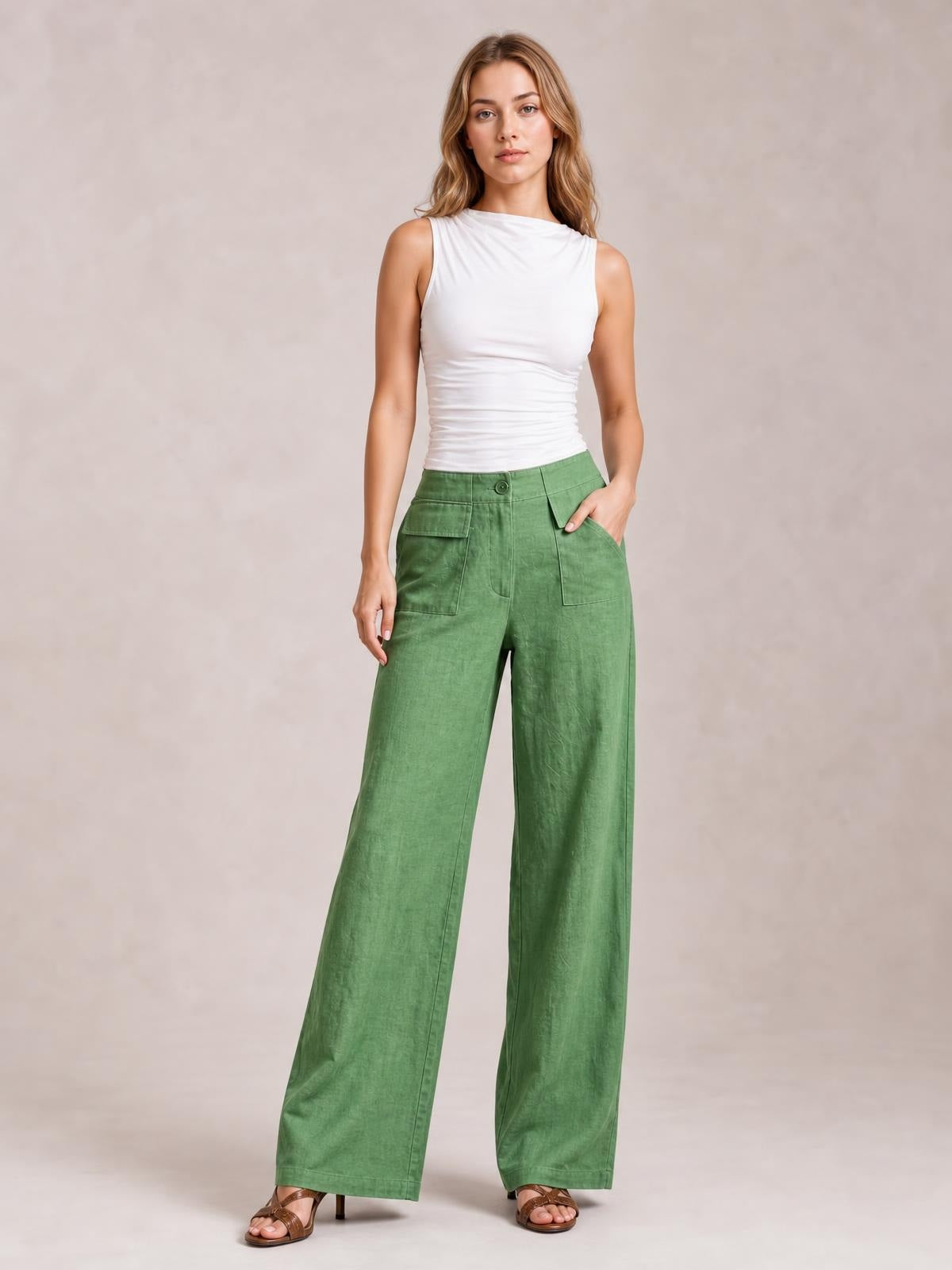 Model poses in green wide leg pants with a buttoned waistband, front patch pockets, side pockets, and relaxed full-length legs.
