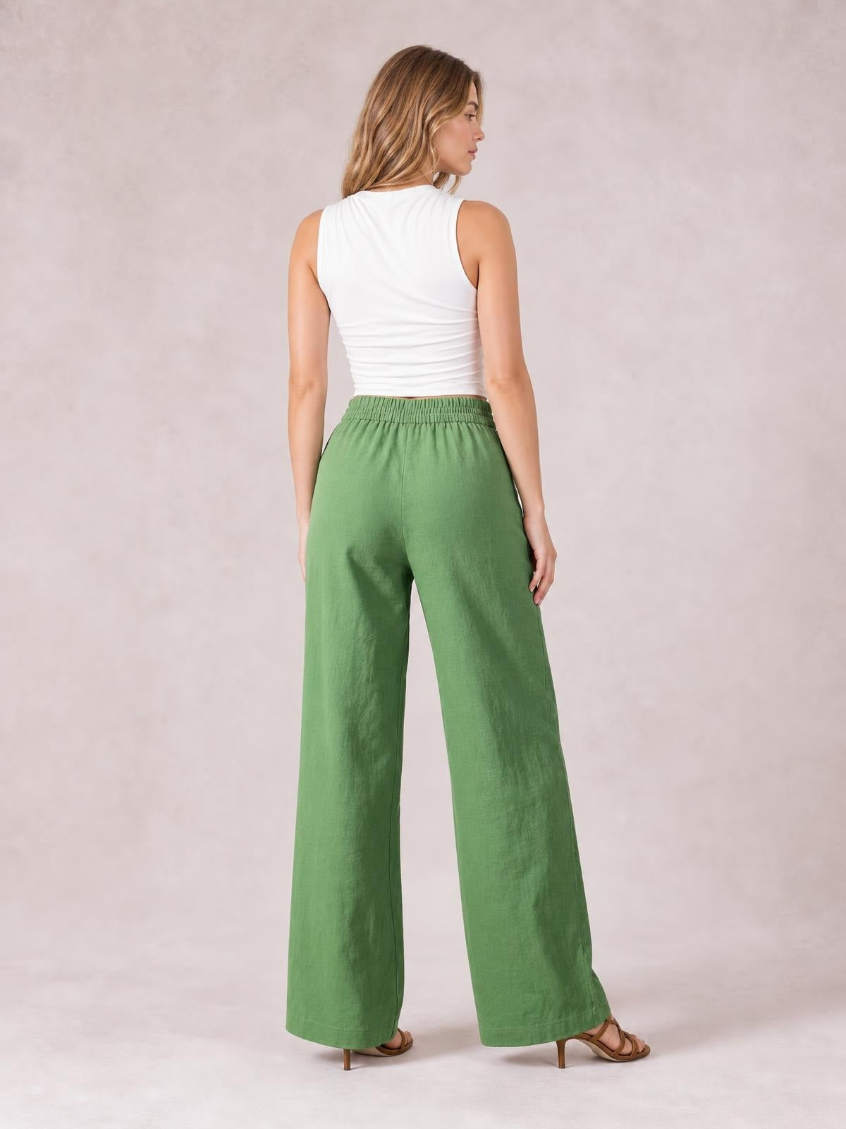 Model in a back-facing pose wears green wide leg pants with a high elastic waistband, relaxed silhouette, and side pockets.