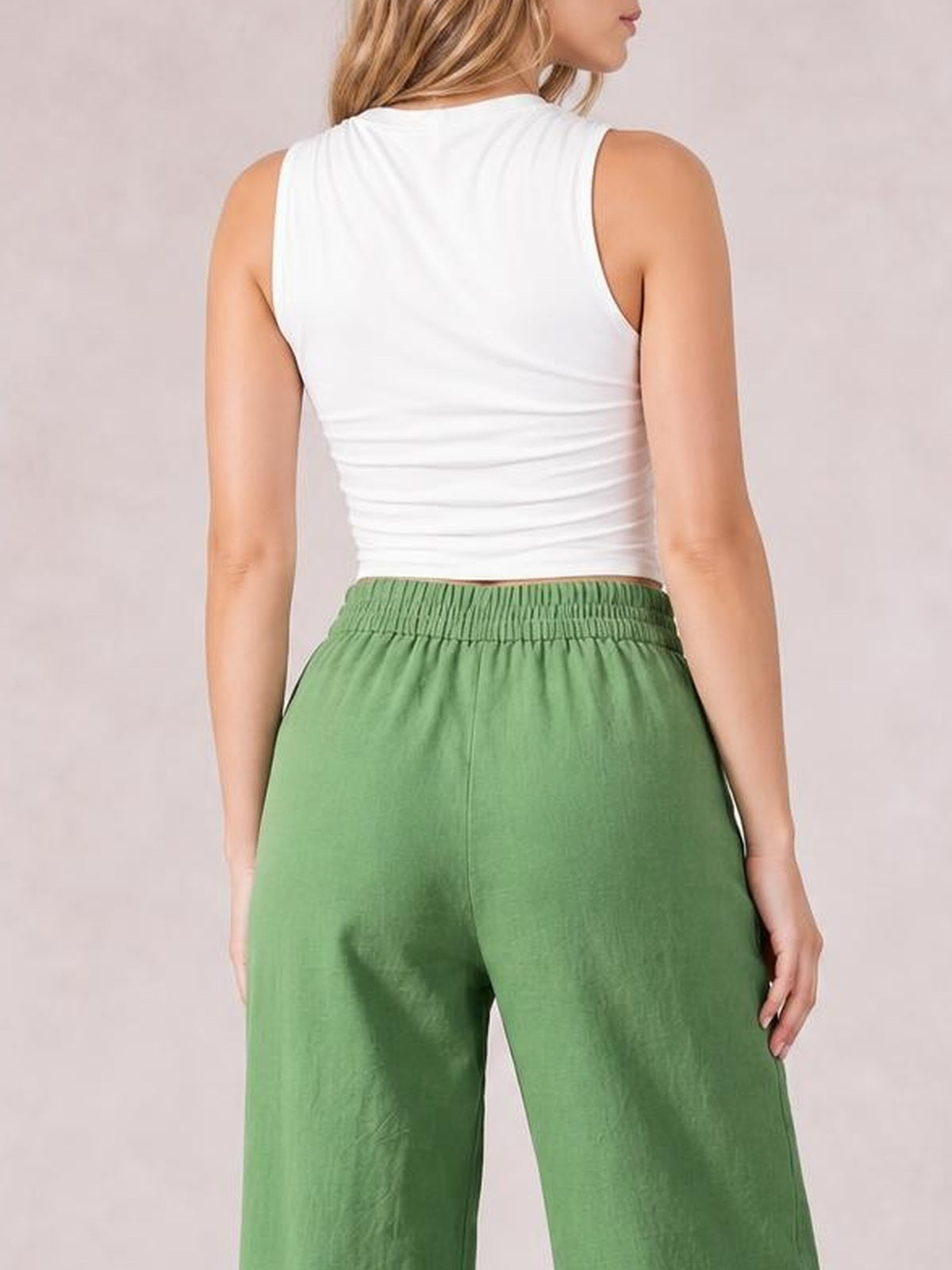Model shown from behind wearing green wide leg pants with a gathered elastic waistband and relaxed silhouette, standing with arms at her sides.