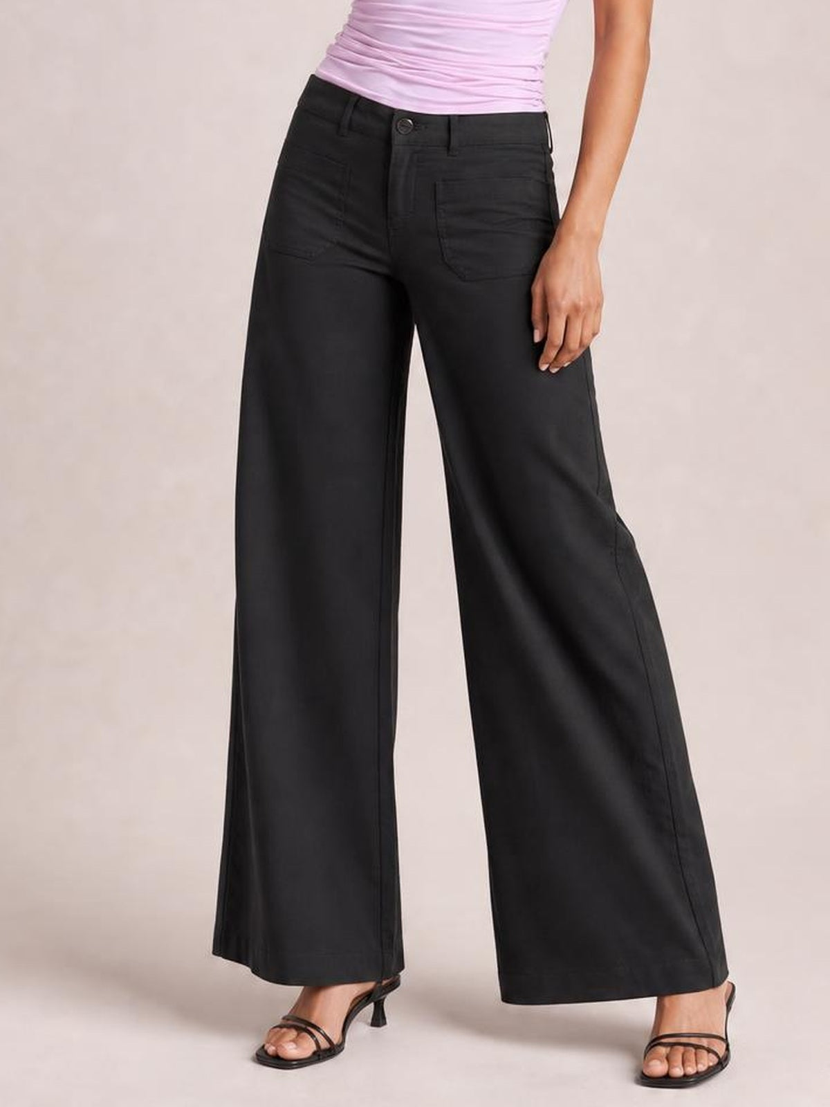 Model wearing black wide-leg pants with front and back pockets, belt loops, button closure, and a relaxed full-length silhouette.