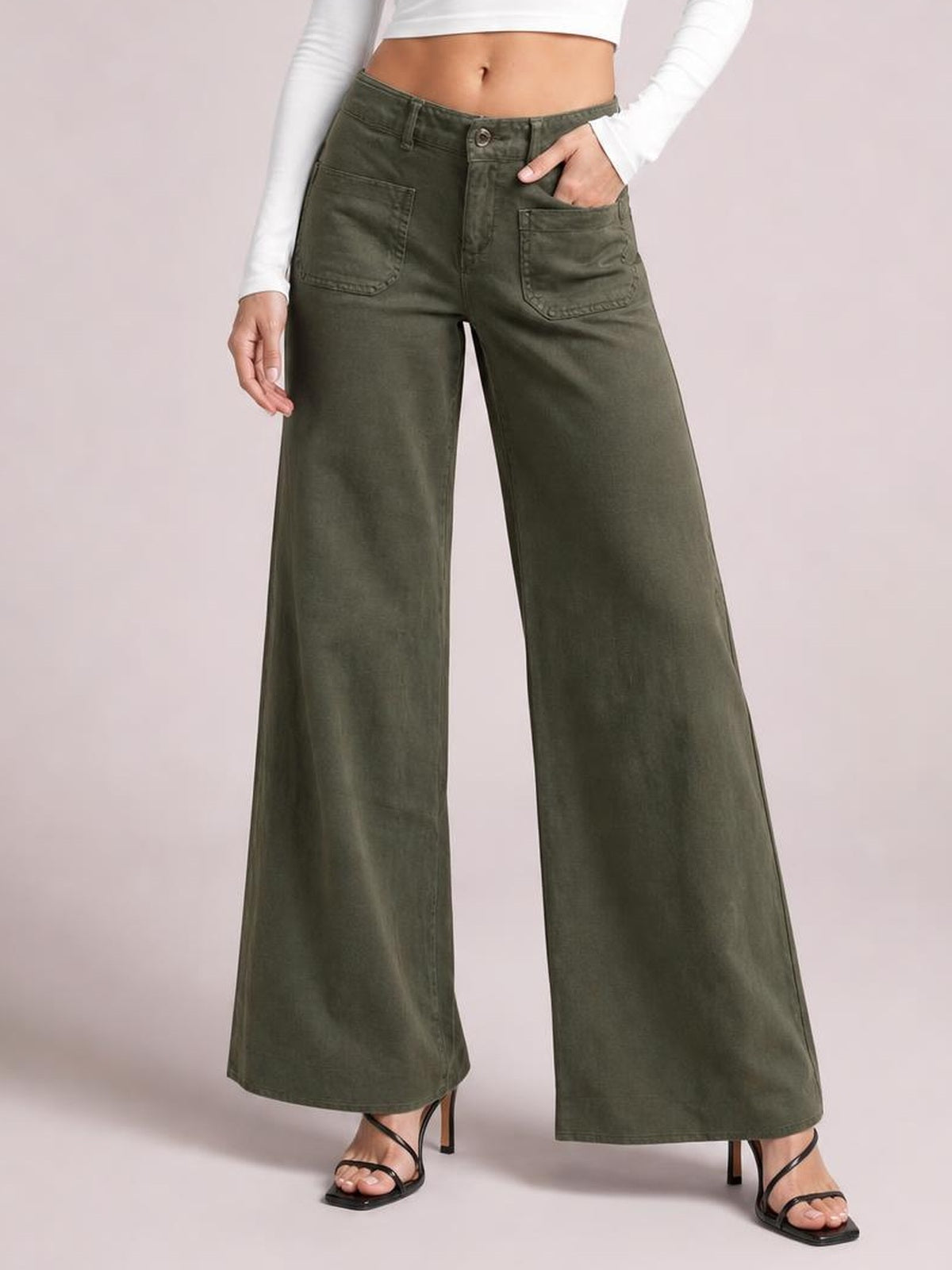 Model poses with one hand in the pocket of olive green wide-leg pants featuring a button closure, belt loops, and two front patch pockets.