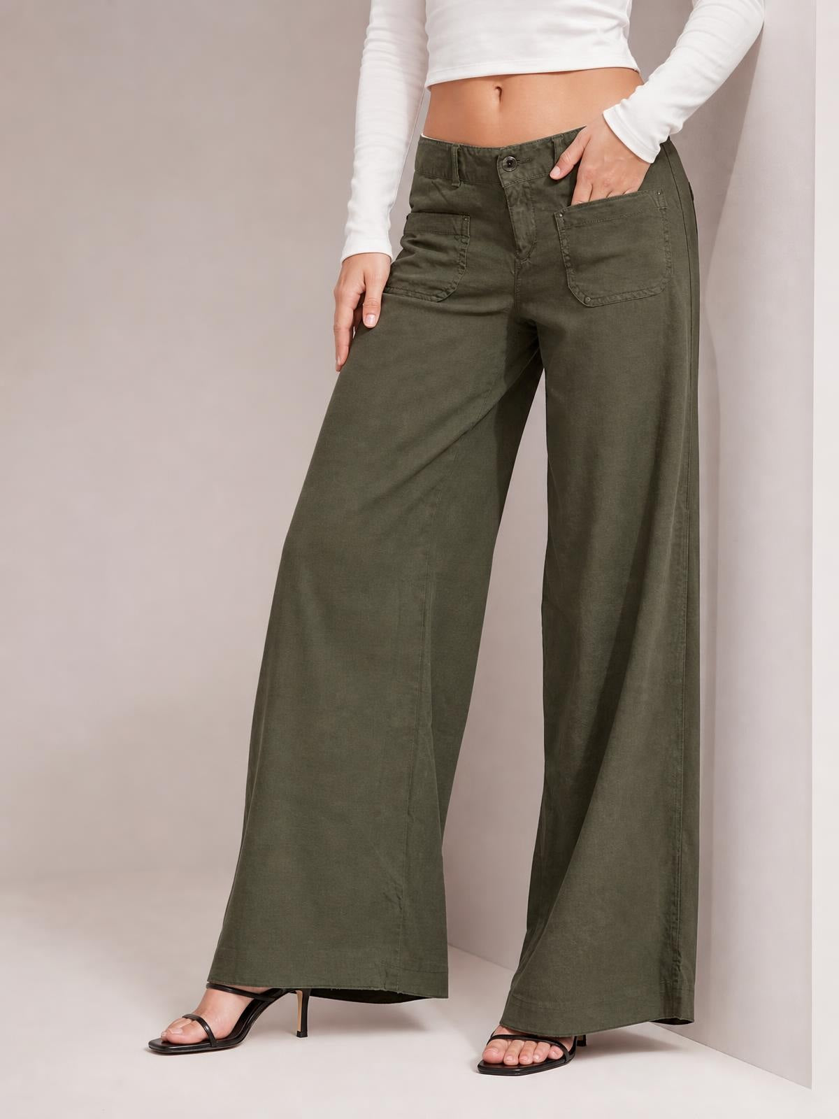Model wearing olive green wide leg pants with front patch pockets, belt loops, button closure, and a full-length relaxed silhouette.