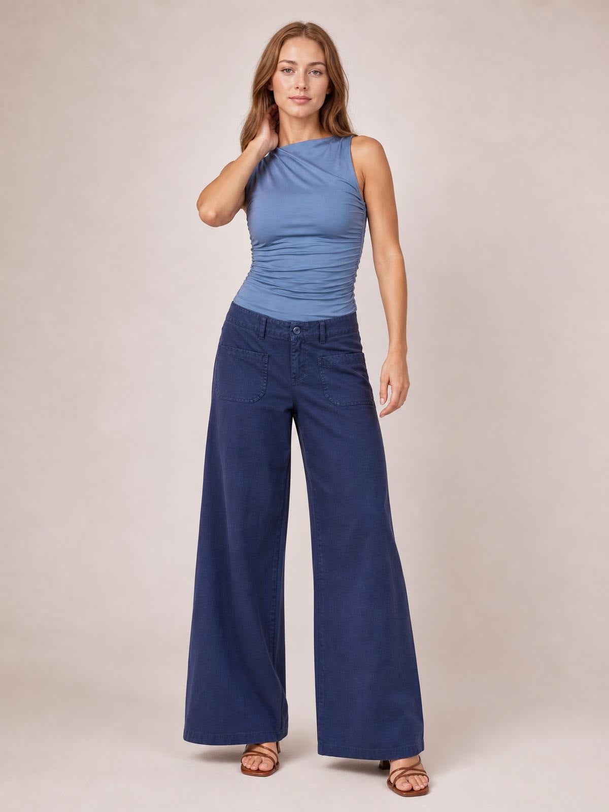 Model poses in navy blue wide leg pants with front pockets, belt loops, button closure, and a full-length relaxed silhouette.