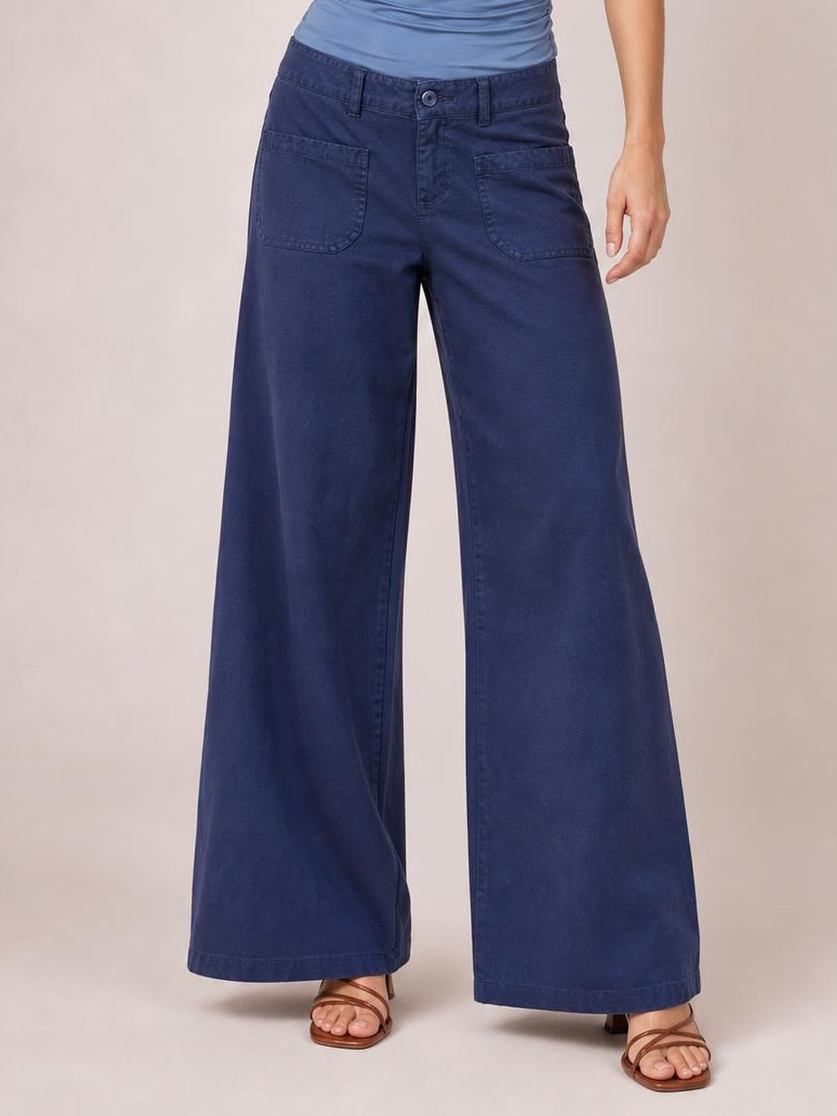 Model wearing navy wide leg pants with front pockets, a button closure, belt loops, and a structured full-length silhouette.