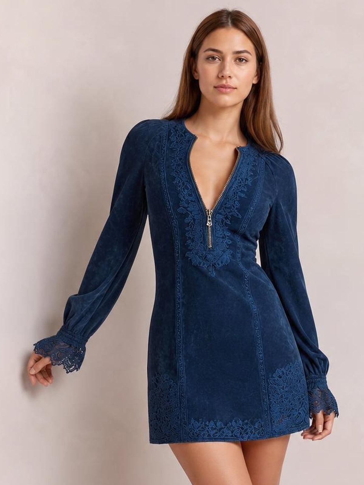 A model poses in a navy blue long-sleeve mini dress with a zip-front neckline, lace detailing, flared silhouette, and lace-trimmed cuffs and hem.