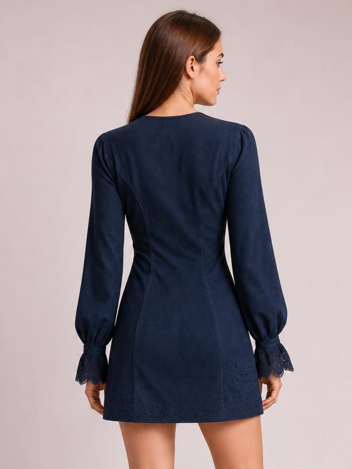 A model wears a navy blue long-sleeve mini dress with a fitted seamed silhouette, gathered cuffs, and delicate lace trim at the cuffs and hem.