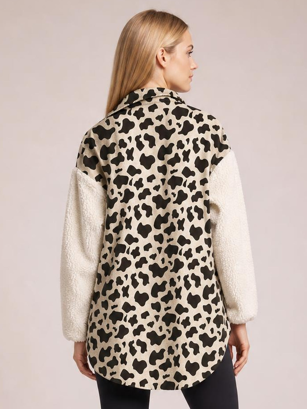 Model shown from the back wears a long-sleeve fuzzy button-up jacket with a beige and black leopard-print body, cream plush sleeves, and a relaxed curved-hem silhouette.