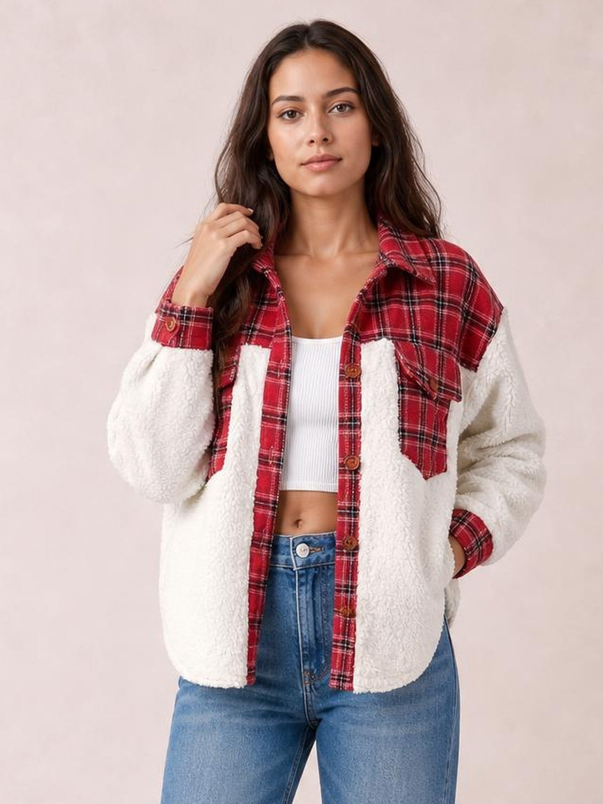 Model poses in a fuzzy white button-up jacket with red plaid panels, long sleeves, a collared silhouette, and visible front pockets.
