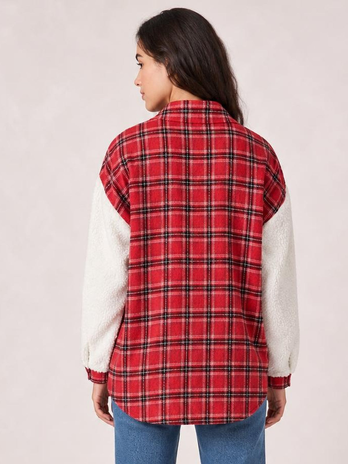 A model shows the back of a red plaid button-up jacket with white fuzzy long sleeves, a collared neckline, relaxed silhouette, and rounded hem.