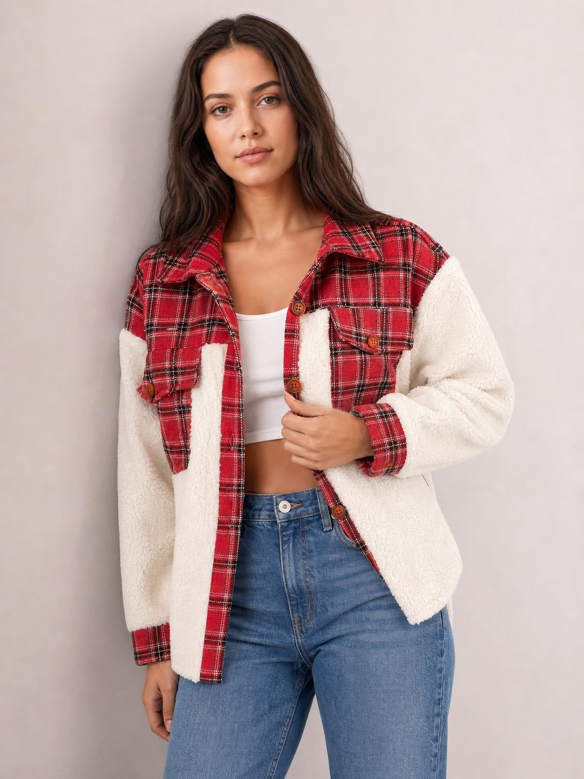 Model wears a red plaid fuzzy button-up jacket with white sherpa sleeves, chest pockets, and a relaxed silhouette, holding the front near the buttons.