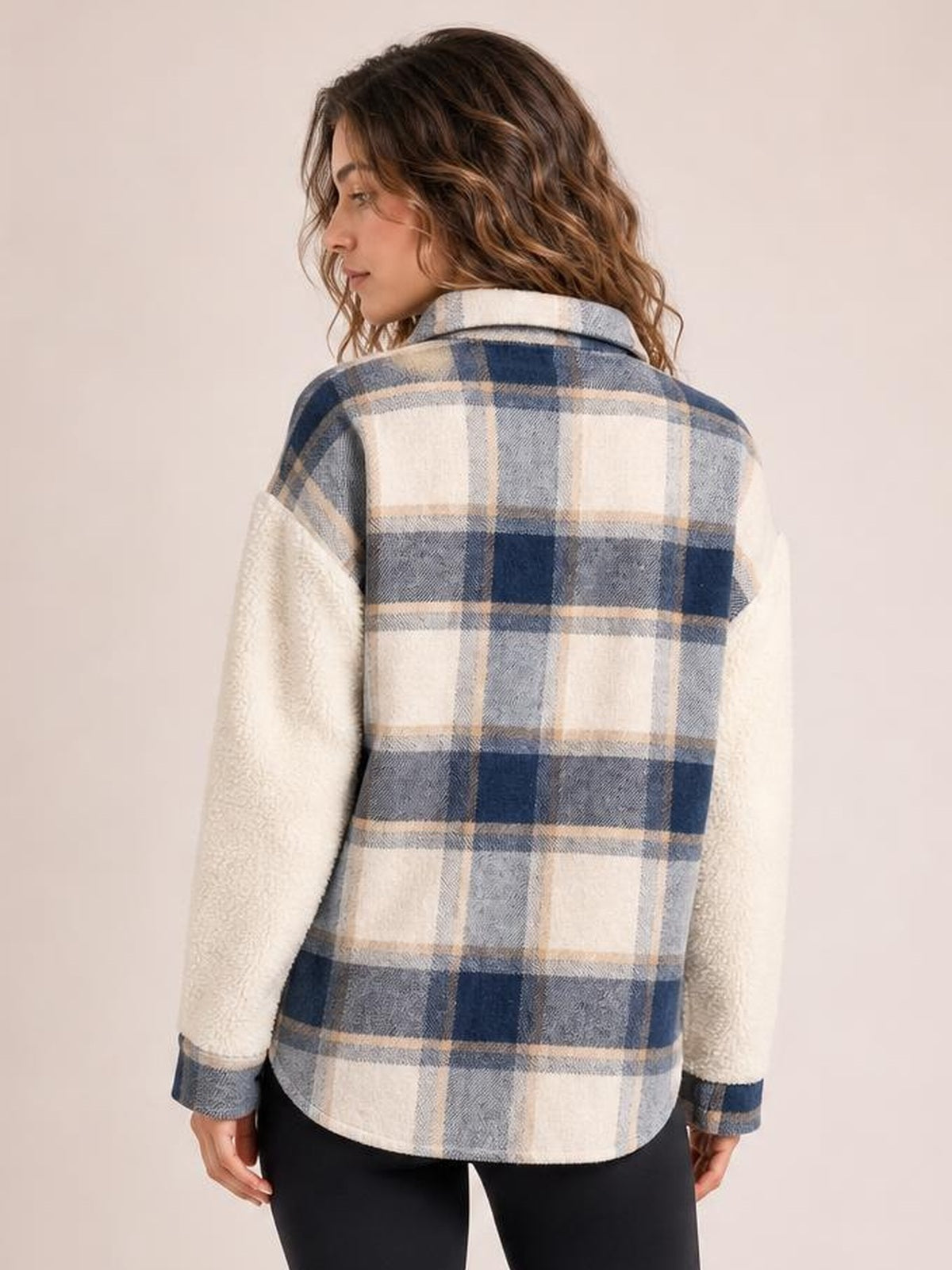 Model turned away to show a fuzzy blue, cream, and gray plaid button-up jacket with a thick shirt-jacket silhouette, long sleeves, and rounded hem.